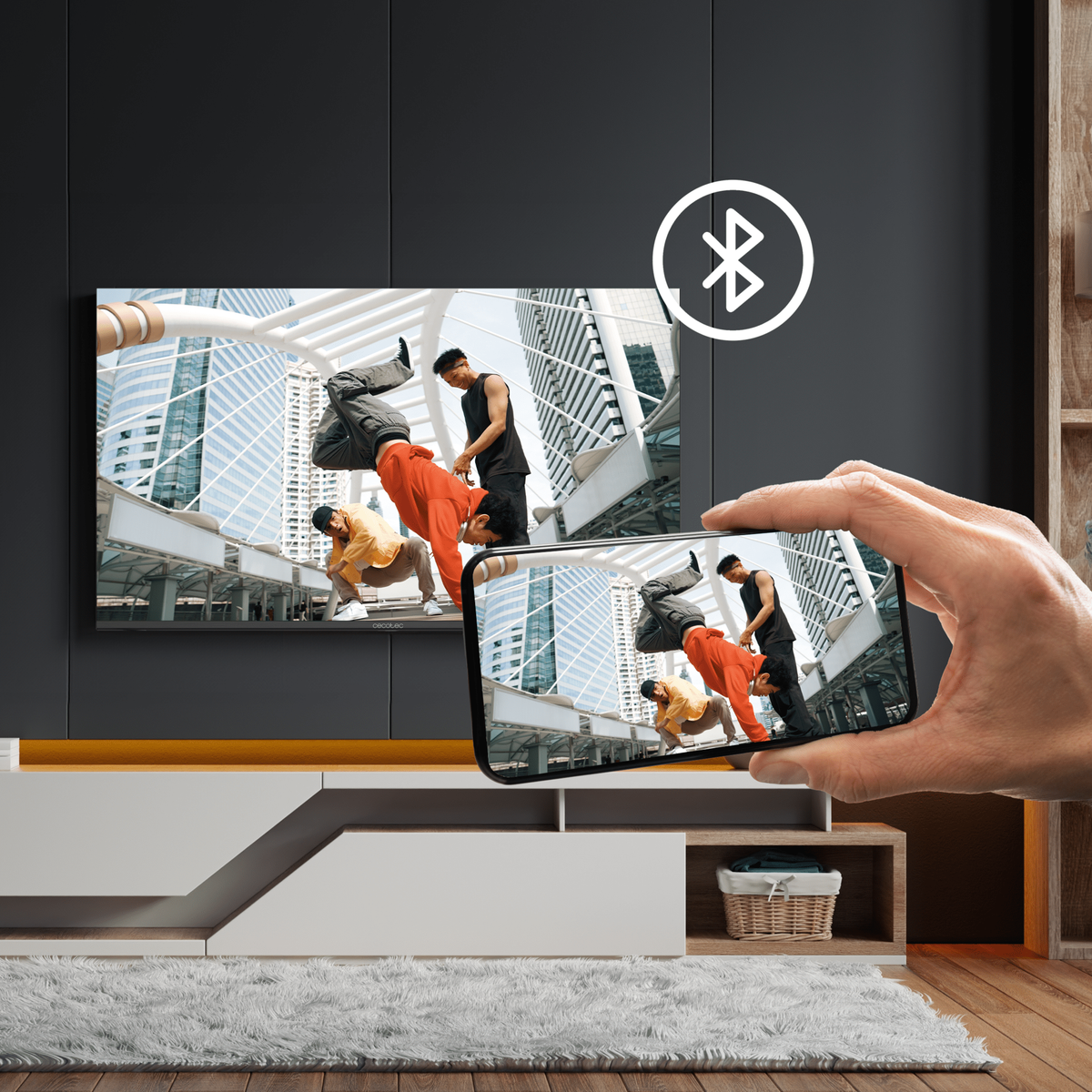 Ekran telewizora pokazujący tancerzy. Telefon wyświetlający ten sam obraz z przodu. Symbol Bluetooth u góry.