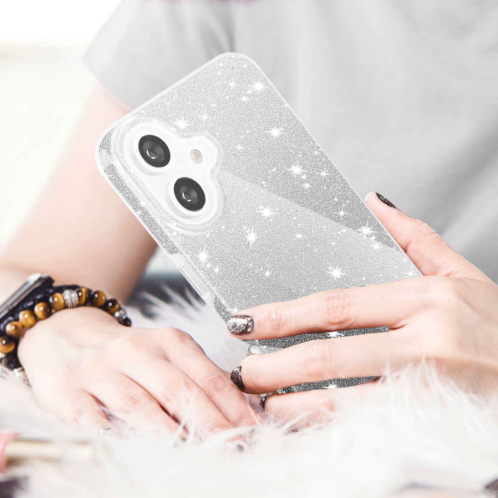 Una donna tiene una cover glitterata per telefono. Le sue mani sono visibili, sfondo sfocato.