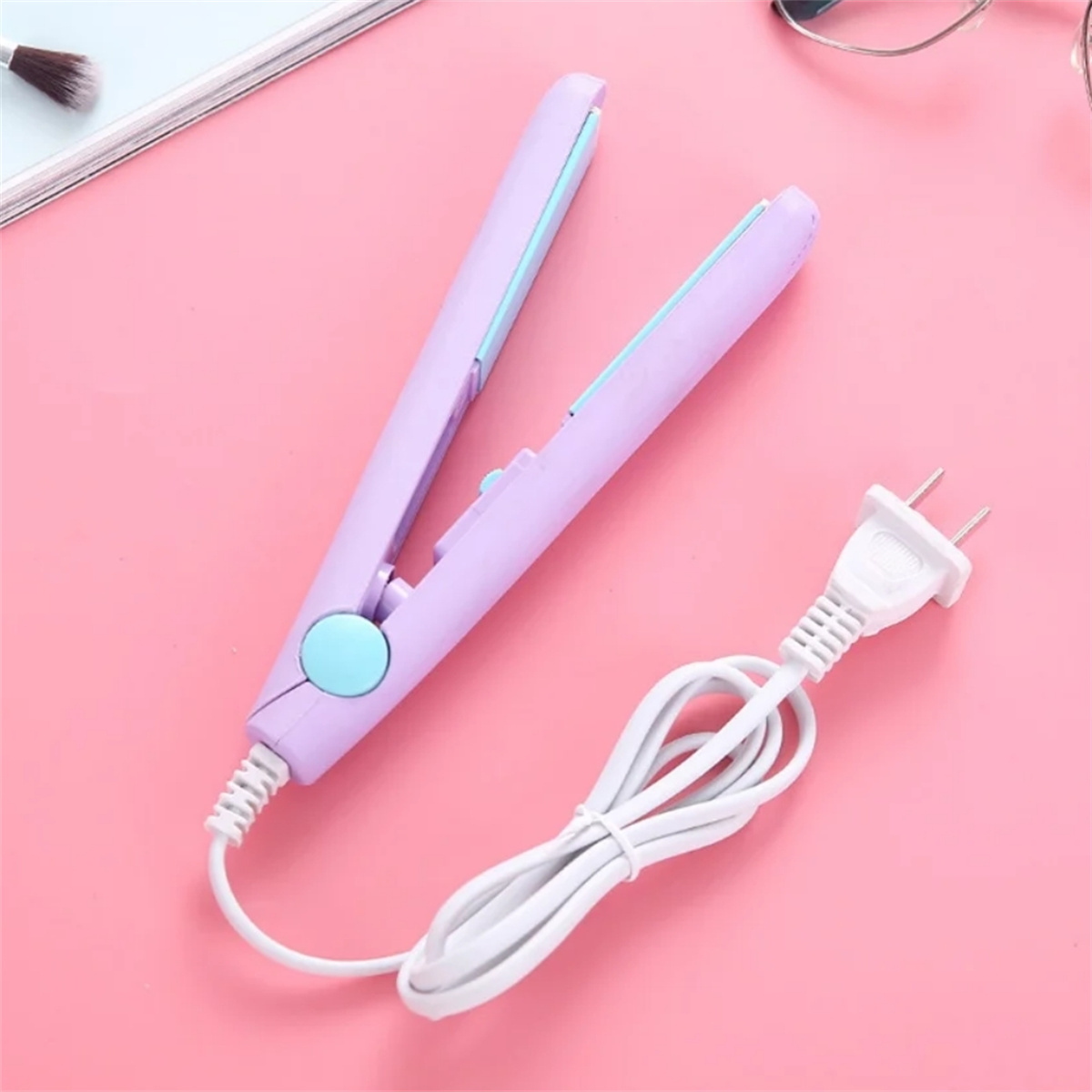 Ein lila Haarglätter mit weißem Kabel und Stecker auf einer pinken Oberfläche. Der Hintergrund ist pink.