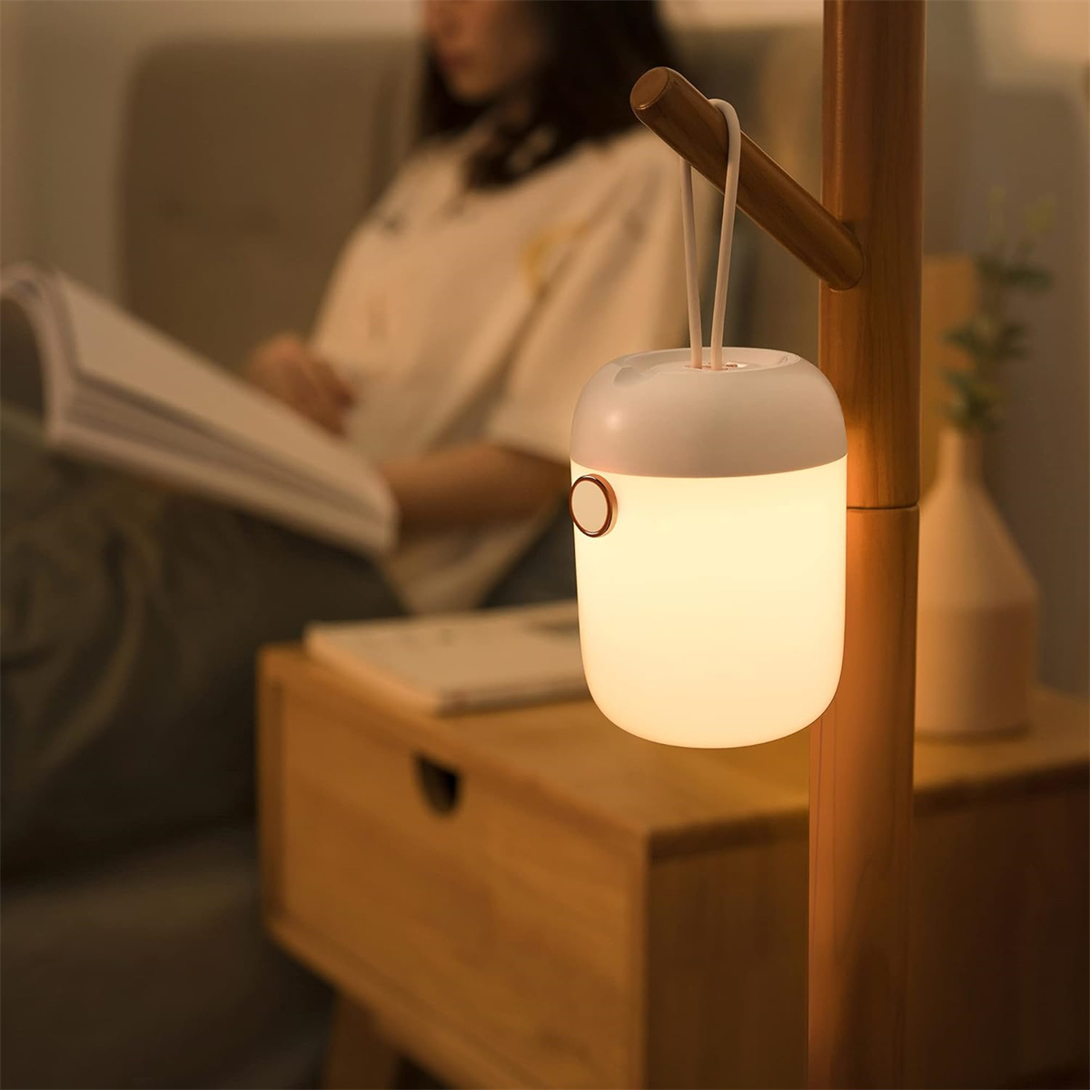 Eine weiße und Holzlampe, die an einem Holzständer hängt, mit verschwommener Person.