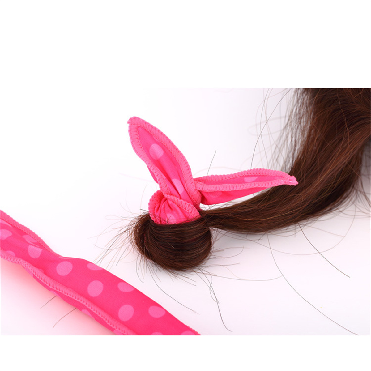 Rosa Haarlocke mit Tupfen, auf weißem Hintergrund, mit braunem Haar.