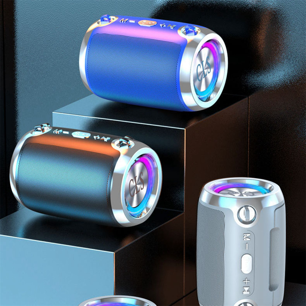 Drei bunte Lautsprecher in einem Stapel, mit Metallringen und Bedientasten. Blau, orange und weiß.