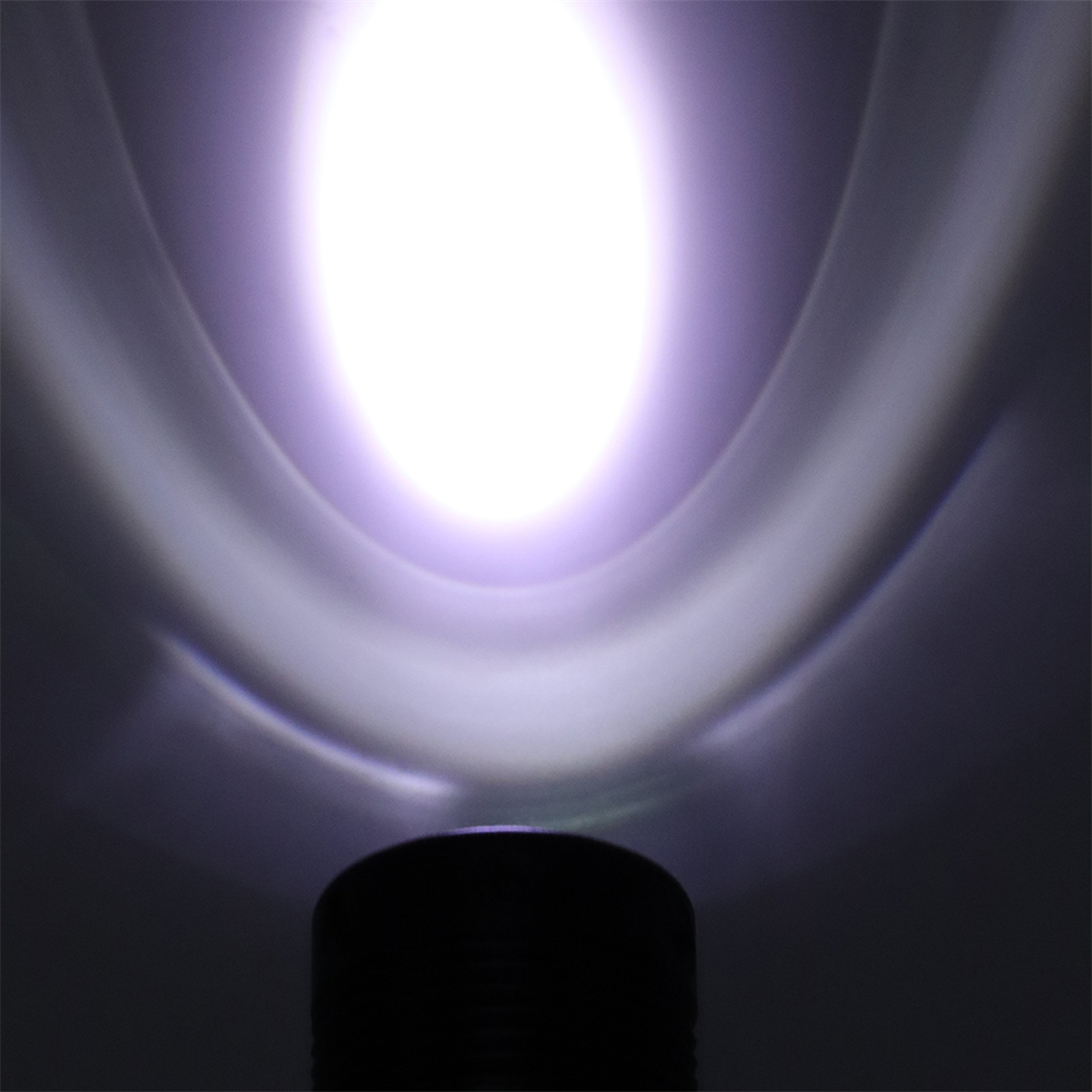 Heller Lichtstrahl von einer schwarzen Taschenlampe. Das Licht ist weiß mit violettem Farbton in dunkler Umgebung.