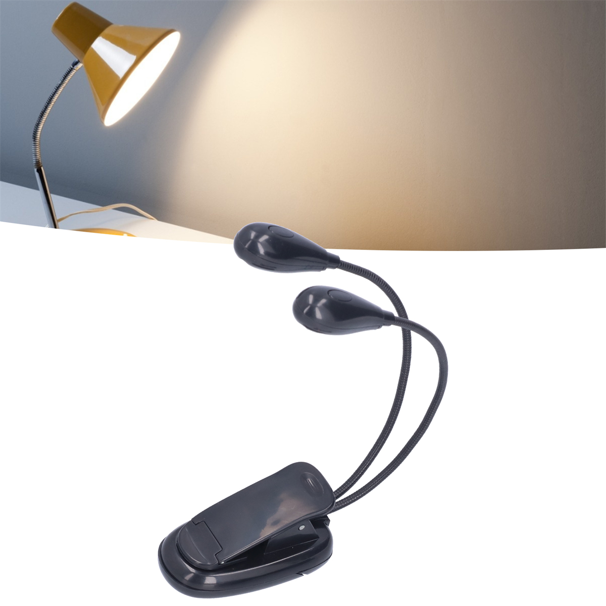Schwarzes Clip-on-Leselicht mit zwei flexiblen Leuchten und gelber Lampe im Hintergrund.