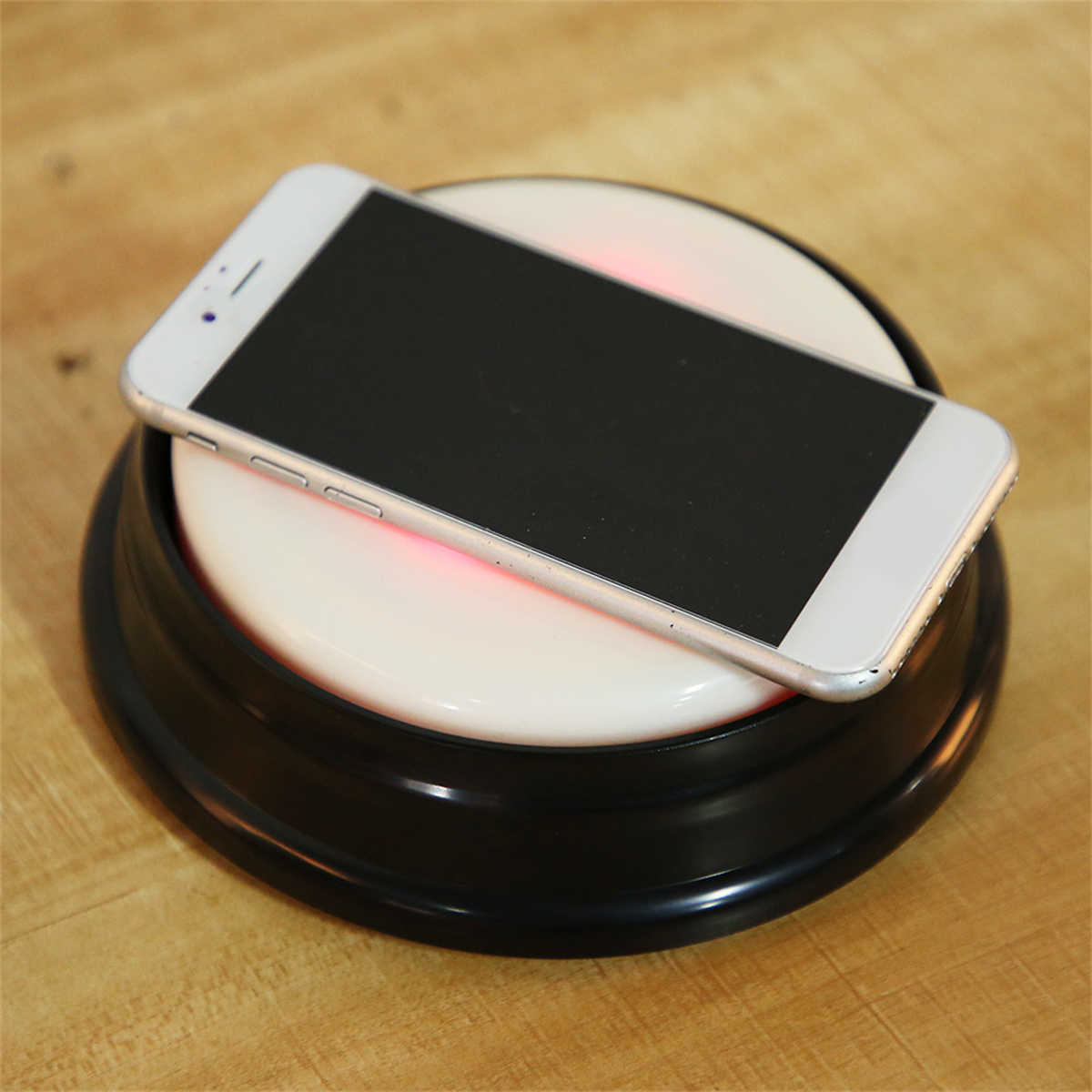 Ein weißes Smartphone liegt auf einem kabellosen Ladepad mit schwarzem Sockel.
