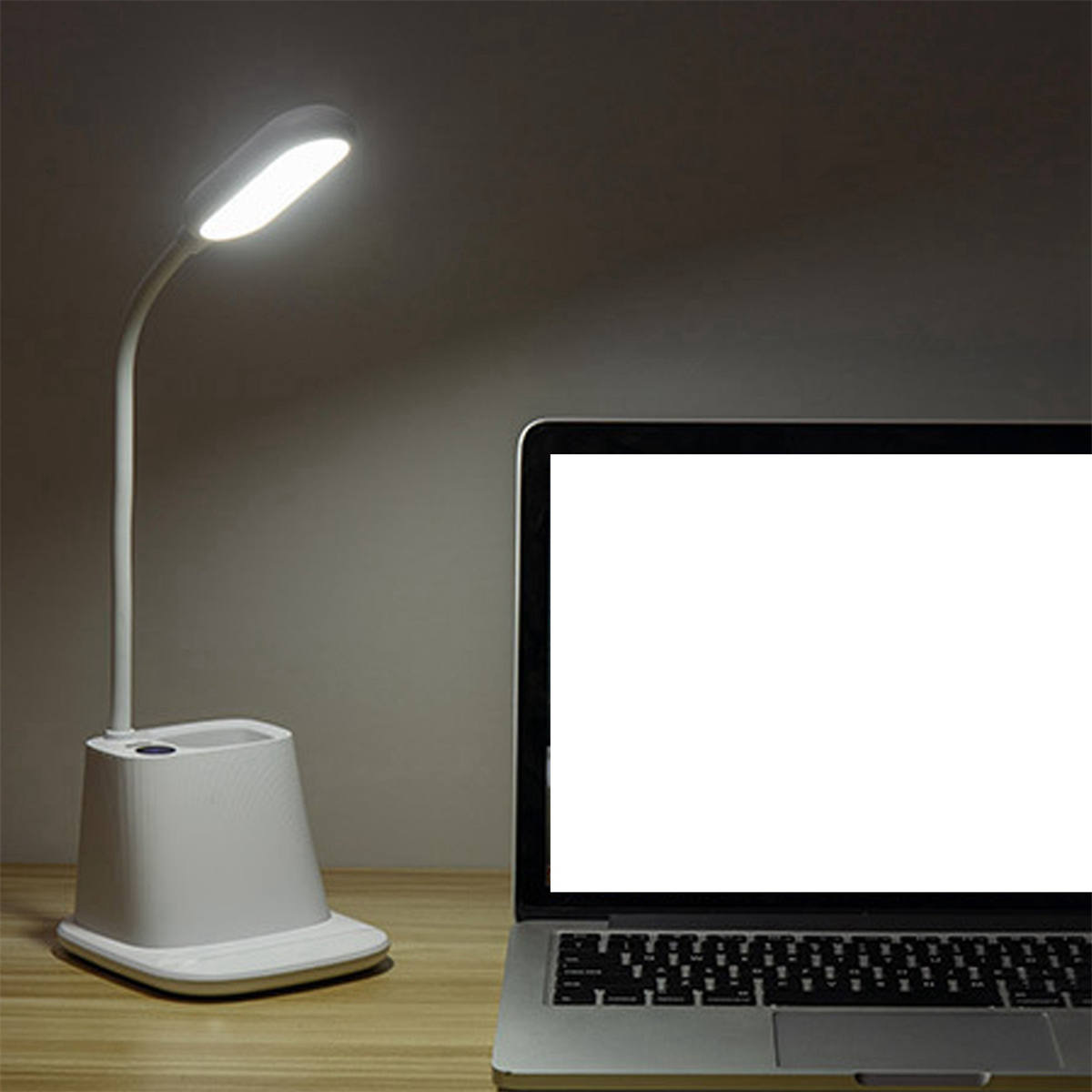 Eine weiße Schreibtischlampe mit flexiblem Hals neben einem Laptop auf einem Holzschreibtisch.