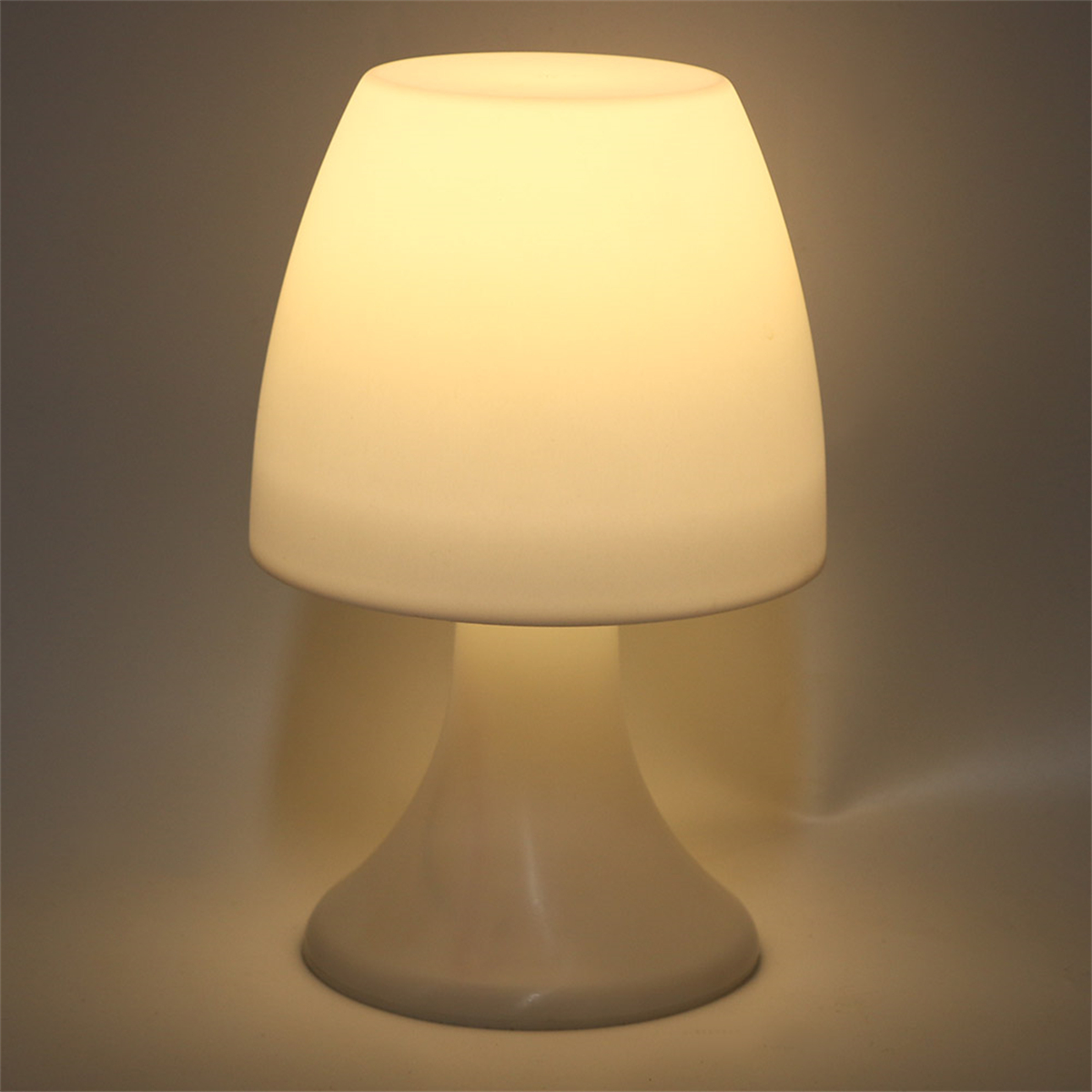 Eine weiße pilzförmige Lampe mit weißem Stiel. Die Lampe steht auf einer weißen Oberfläche.