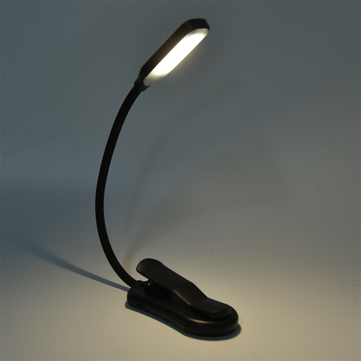 Eine schwarze, flexible Leselampe, die an einer Basis befestigt ist und helles Licht aussendet.