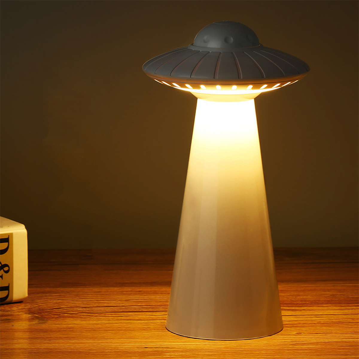 Eine UFO-förmige Lampe mit grauem Körper und weißem Licht, das von unten emittiert wird.