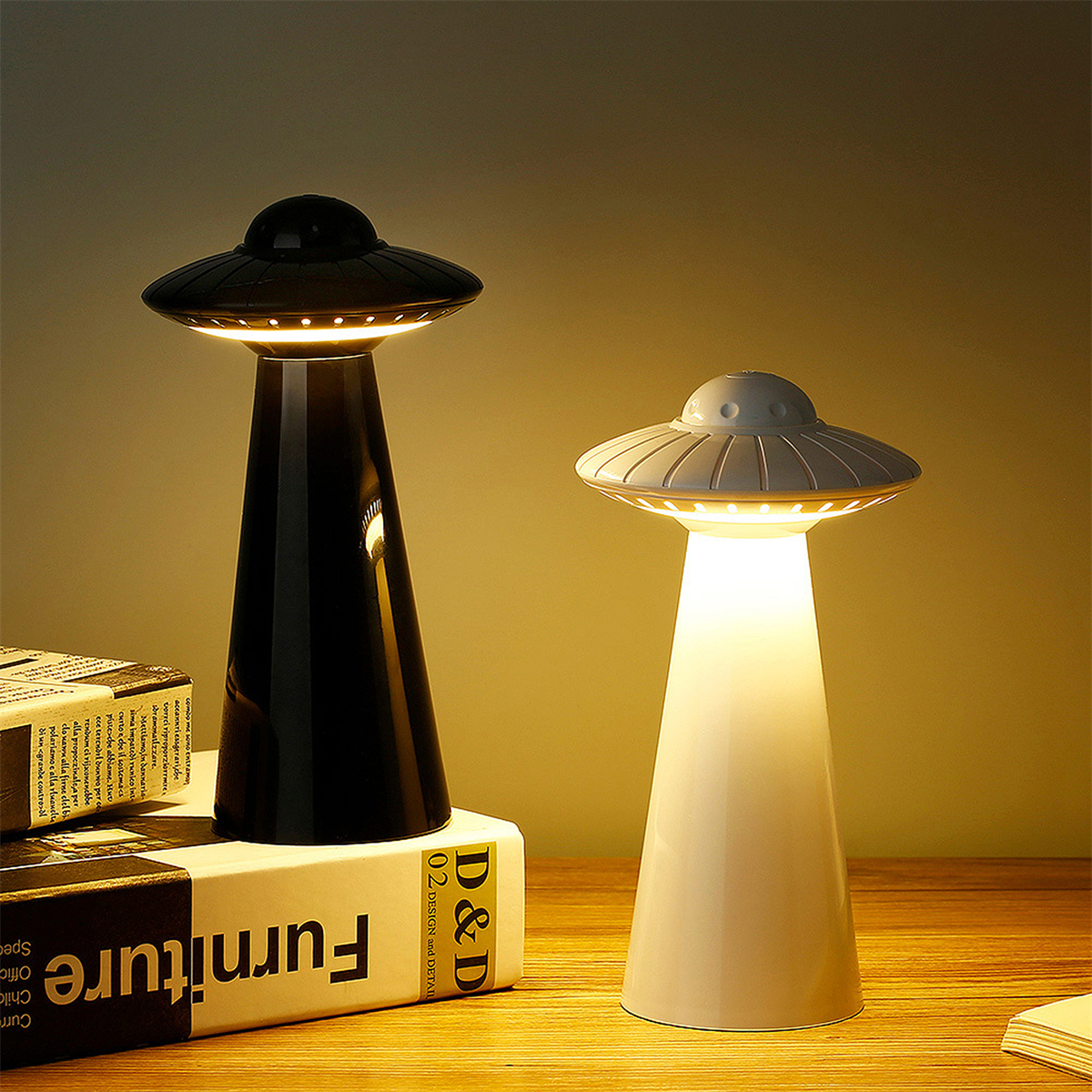 Zwei außerirdisch geformte Lampen, eine schwarz, eine weiß, auf Büchern stehend. Beide sind hell beleuchtet.