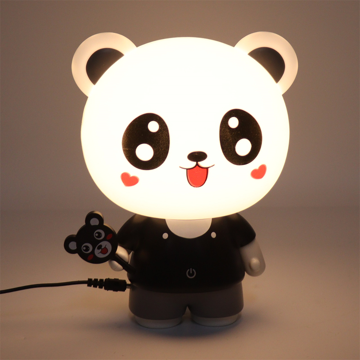 Pandaförmige Lampe mit Licht. Sie hat ein schwarzes Hemd und ein Pandaspielzeug.