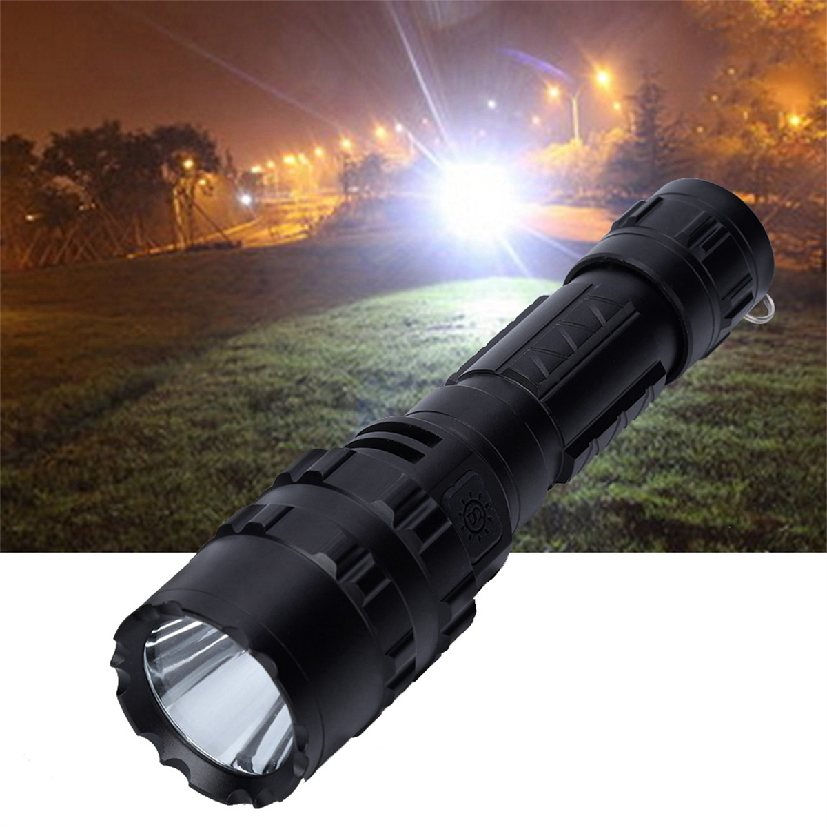 Schwarze Taschenlampe, die auf Licht gerichtet ist. Das Licht ist hell und weit entfernt. Der Hintergrund ist ein dunkler, grasbewachsener Bereich.