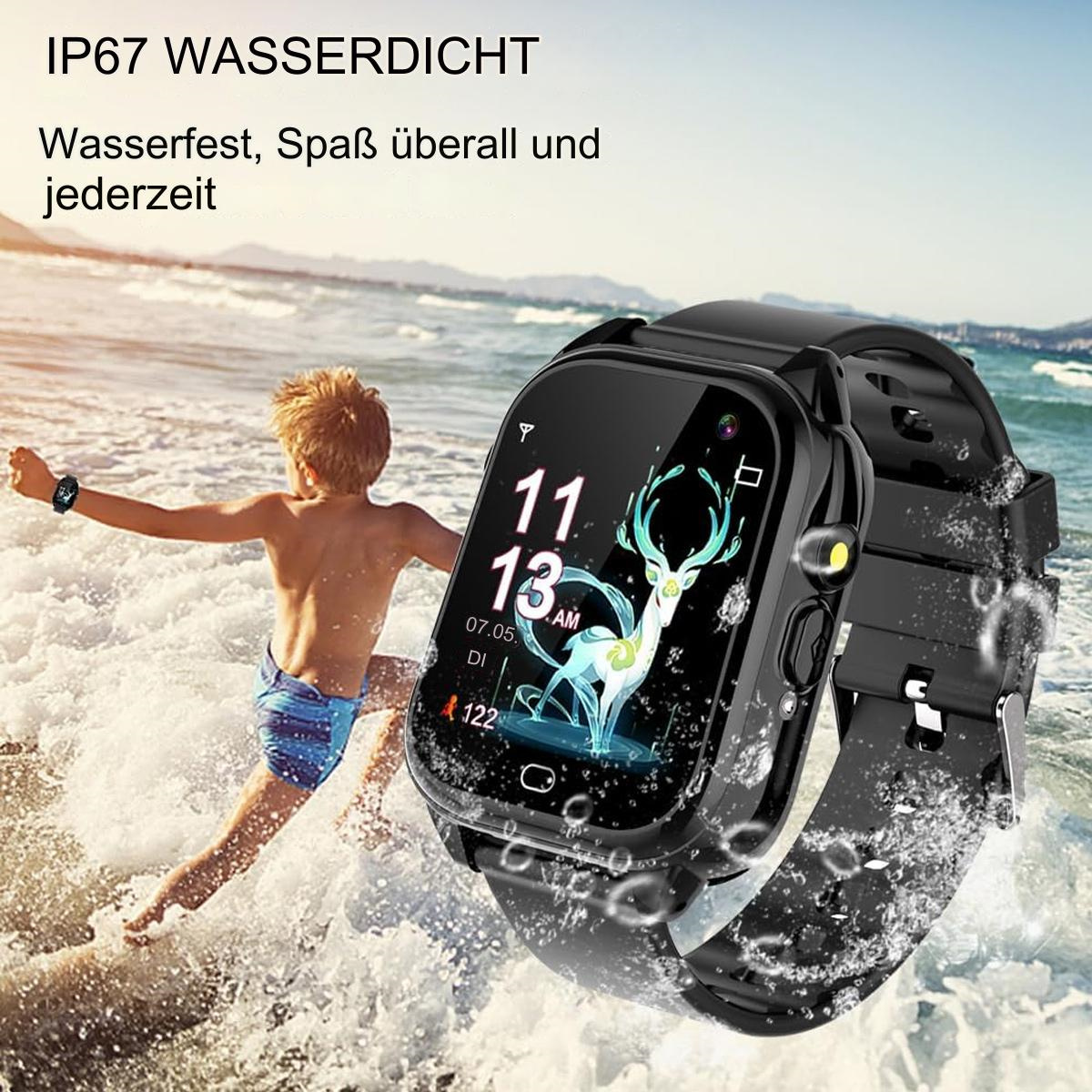 Eine schwarze Smartwatch auf dem Sand mit spritzendem Wasser. Ein Junge springt im Hintergrund ins Meer.