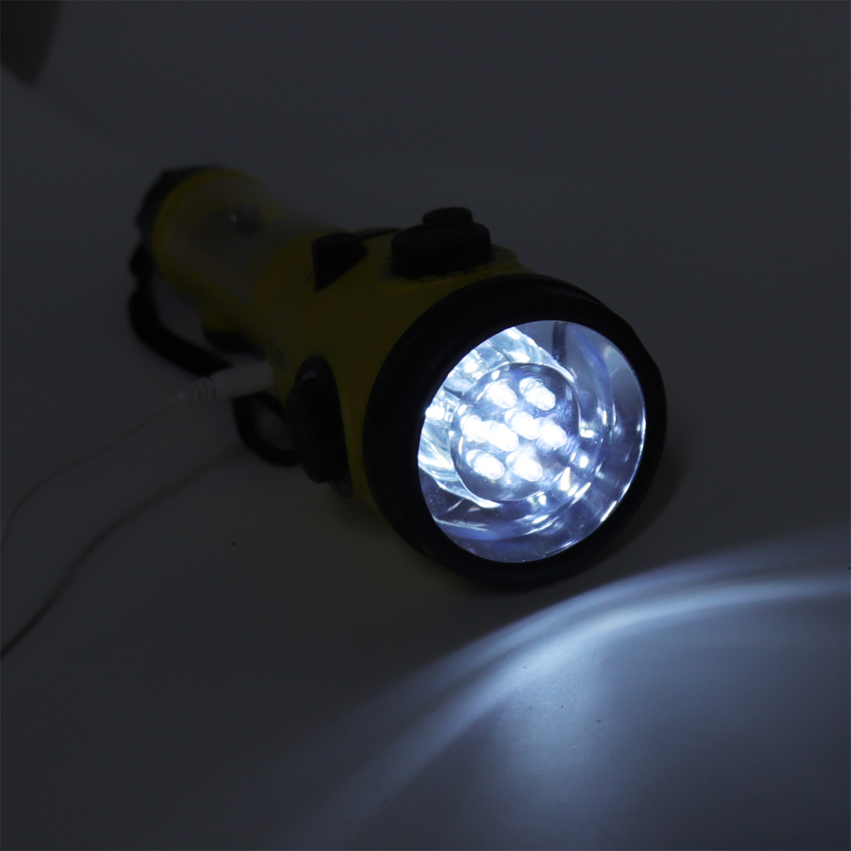 Eine gelbe Taschenlampe mit hellem, weißem Licht, das nach vorne scheint. Der Hintergrund ist dunkel.