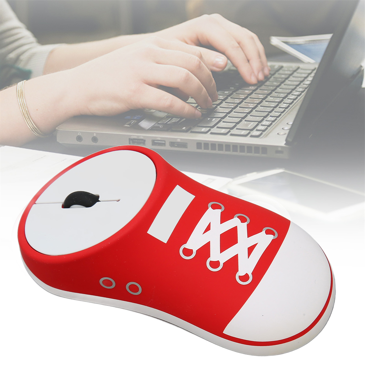Rote mausförmige Maus mit weißen Schnürsenkeln und Laptop mit tippenden Händen.