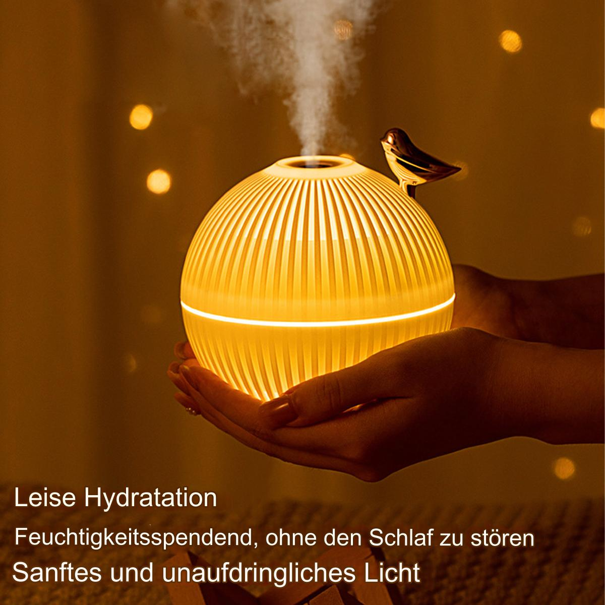 Gelber Luftbefeuchter mit Vogel. Hände halten ihn. Goldener Hintergrund mit sanften Lichtern.