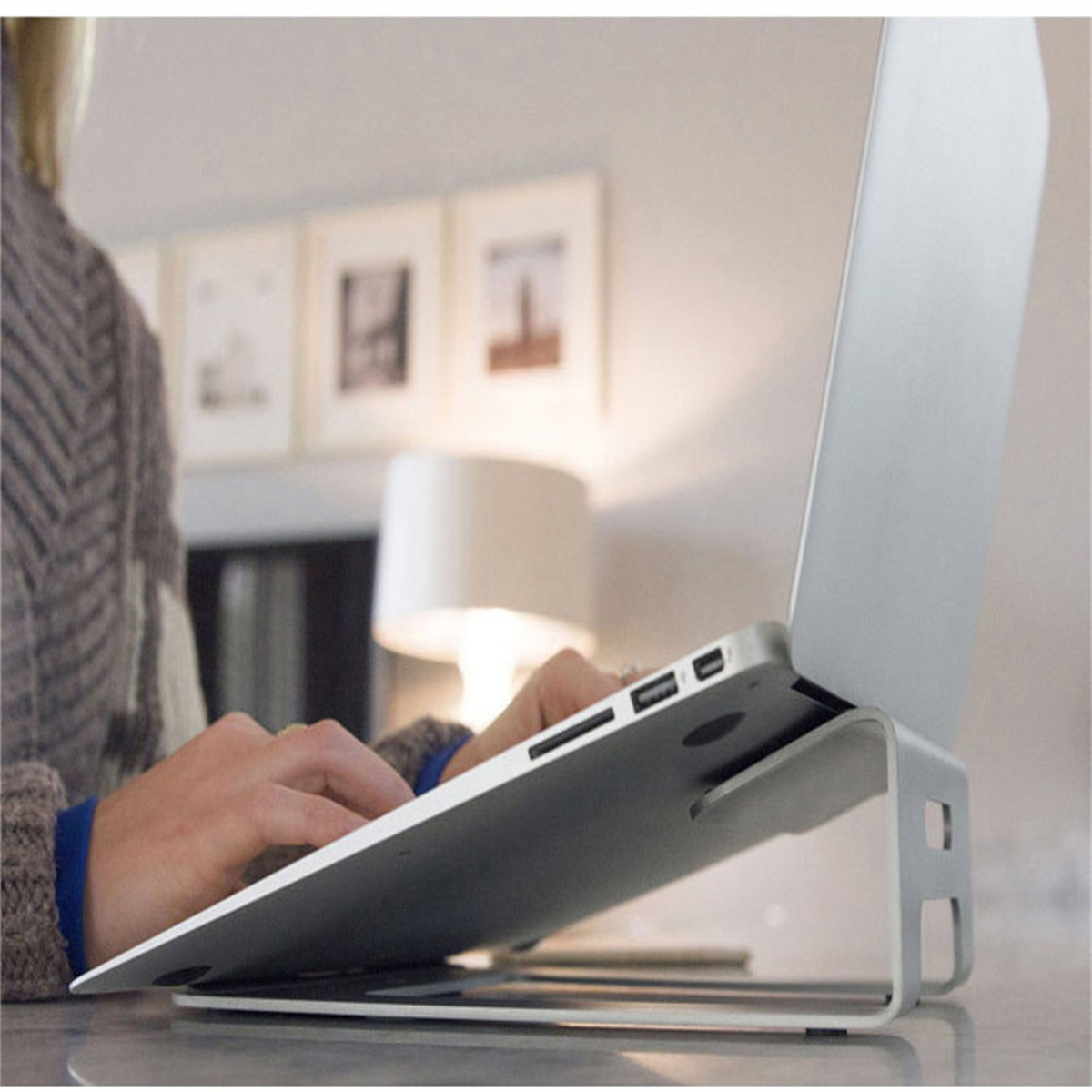 Ein Laptop steht auf einem silbernen Ständer, die Hände des Benutzers auf der Tastatur.