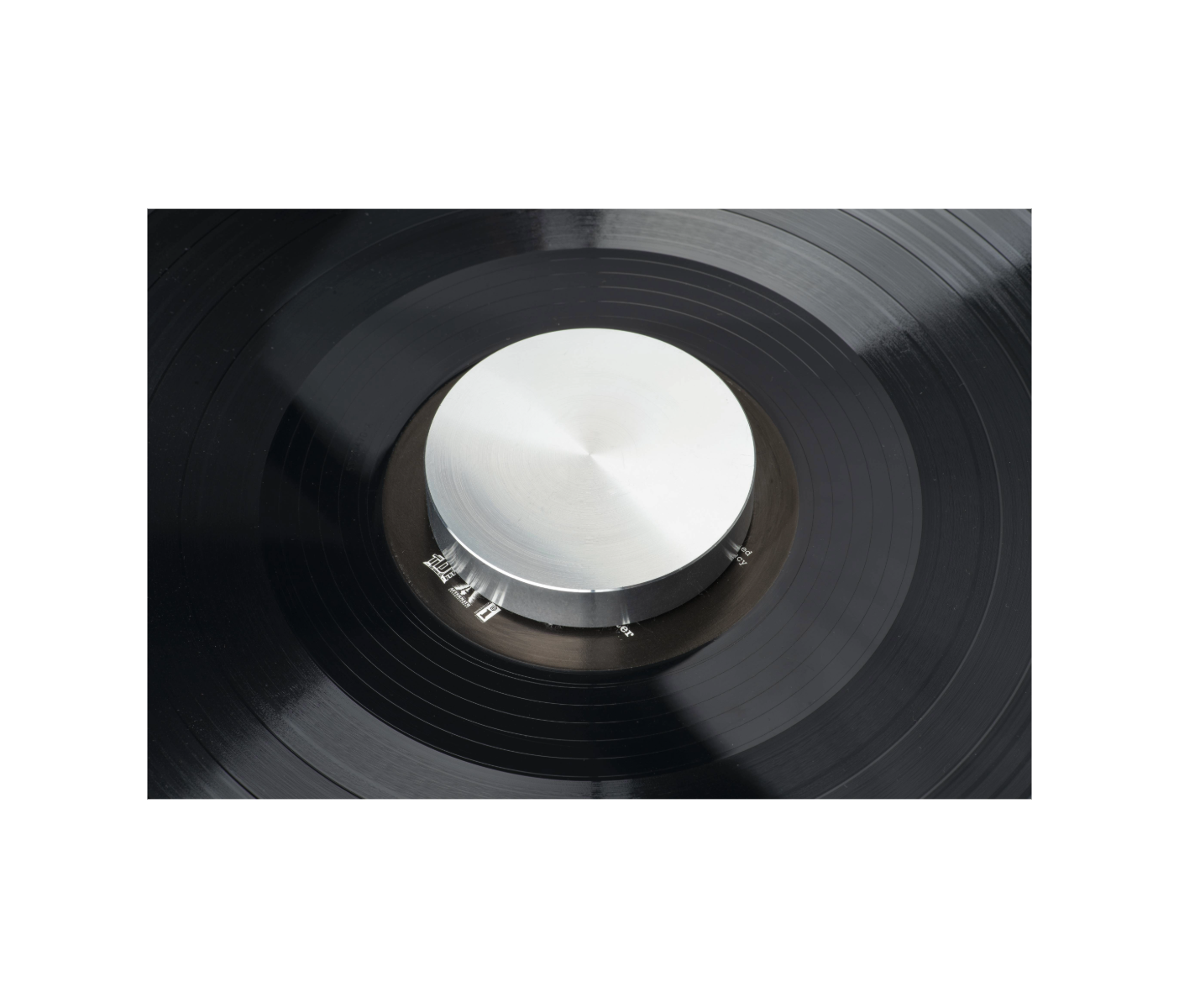 Zbliżenie czarnej płyty winylowej na gramofonie. Widoczny srebrny centralny hub i czarne rowki.