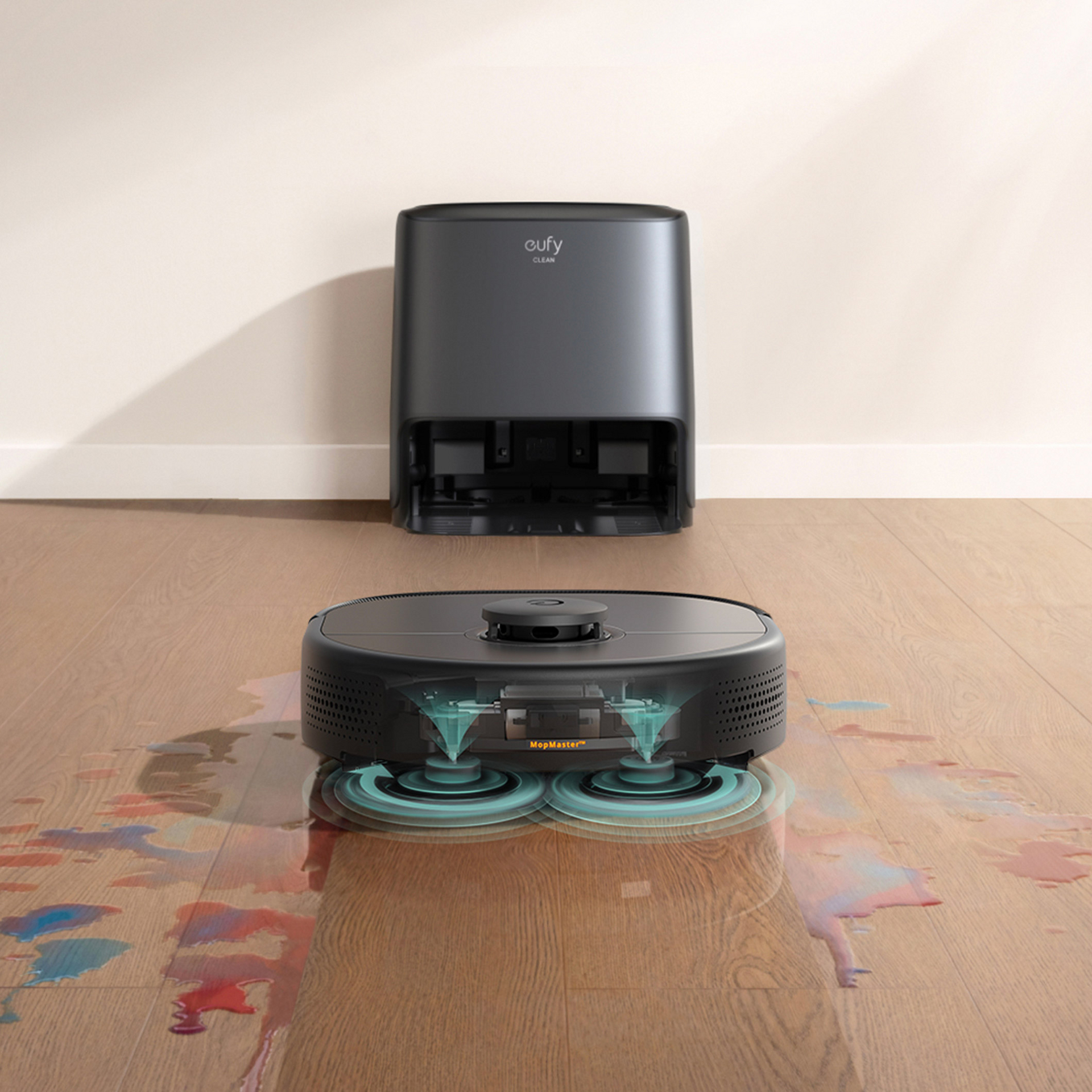 Ein schwarzer Roboter-Staubsauger mit Dockingstation auf einem Holzboden. Wasserflecken sind sichtbar.