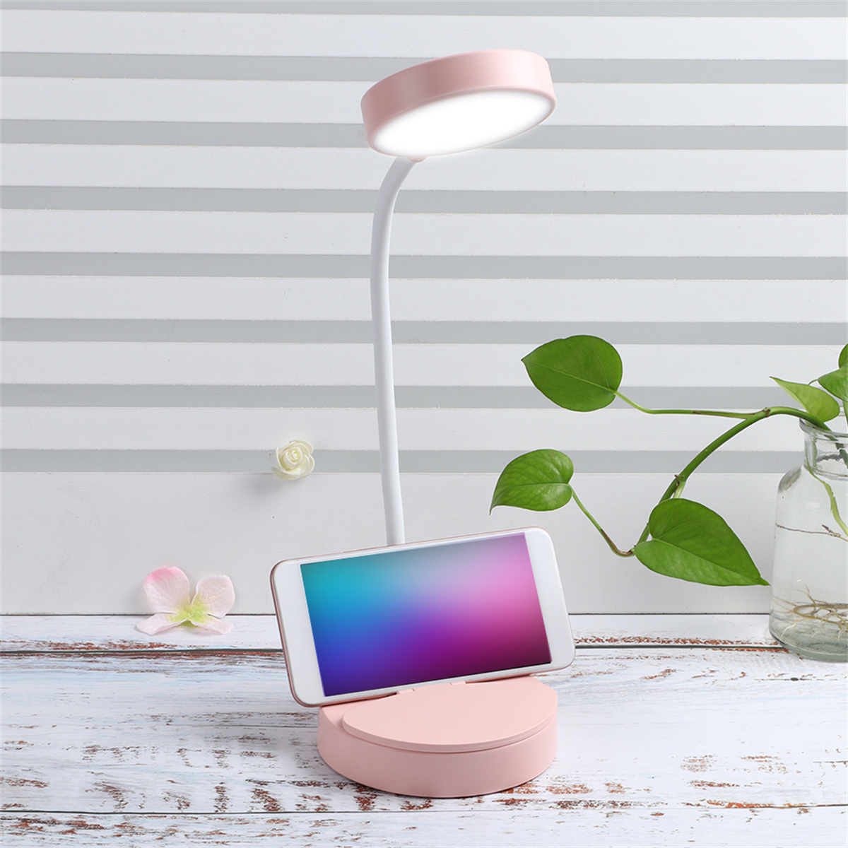 Rosa Schreibtischlampe mit Telefon und Pflanze.
