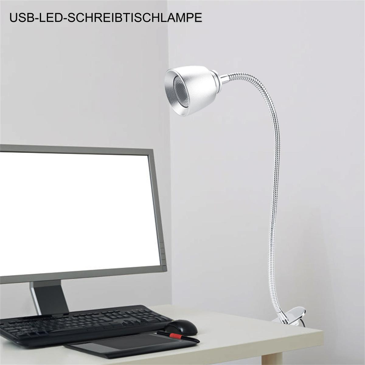 Eine silberne Schreibtischlampe mit flexiblem Hals steht auf einem weißen Schreibtisch, in der Nähe eines Computers und einer Tastatur.
