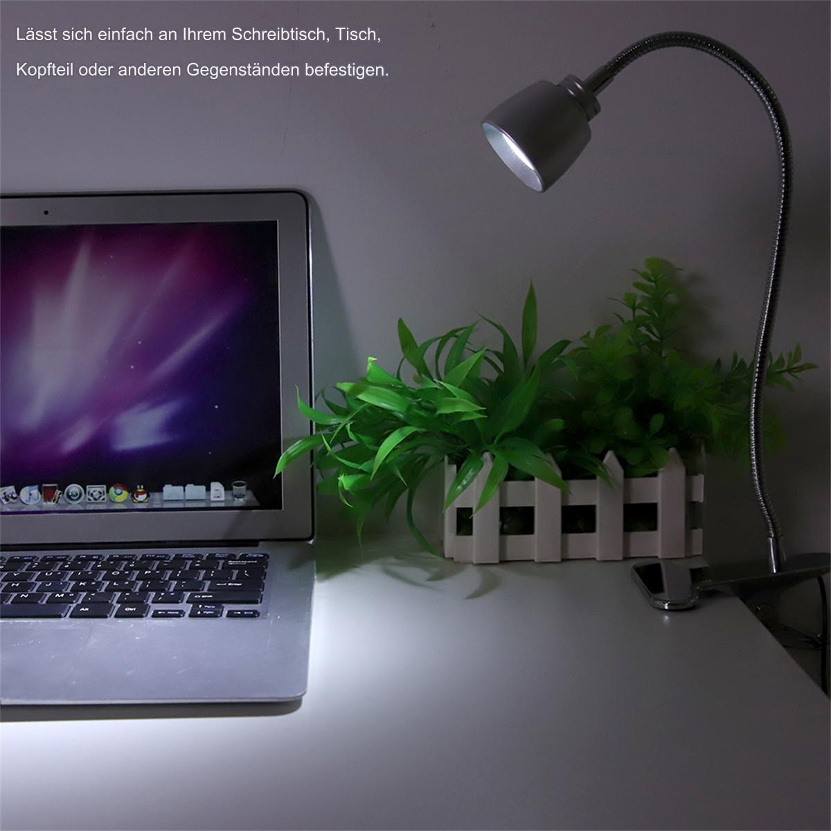 Schreibtischlampe mit flexiblem Arm auf einem Schreibtisch. Es gibt einen Laptop und Pflanzen.
