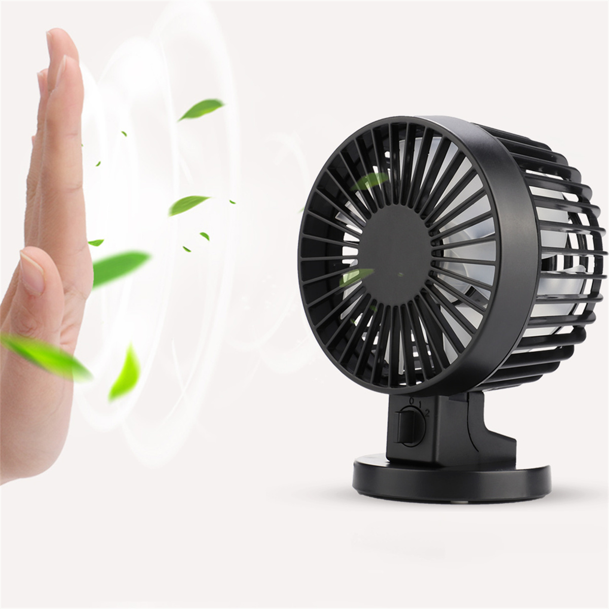 Schwarzer Ventilator mit Hand in der Nähe, grüne Blätter schweben. Der Ventilator steht auf weißem Untergrund.