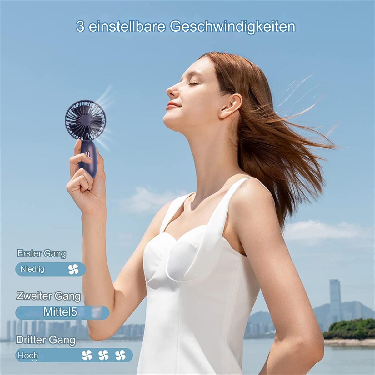 Eine Frau benutzt einen kleinen tragbaren Ventilator. Der Ventilator ist dunkelblau. Der Hintergrund ist blauer Himmel.