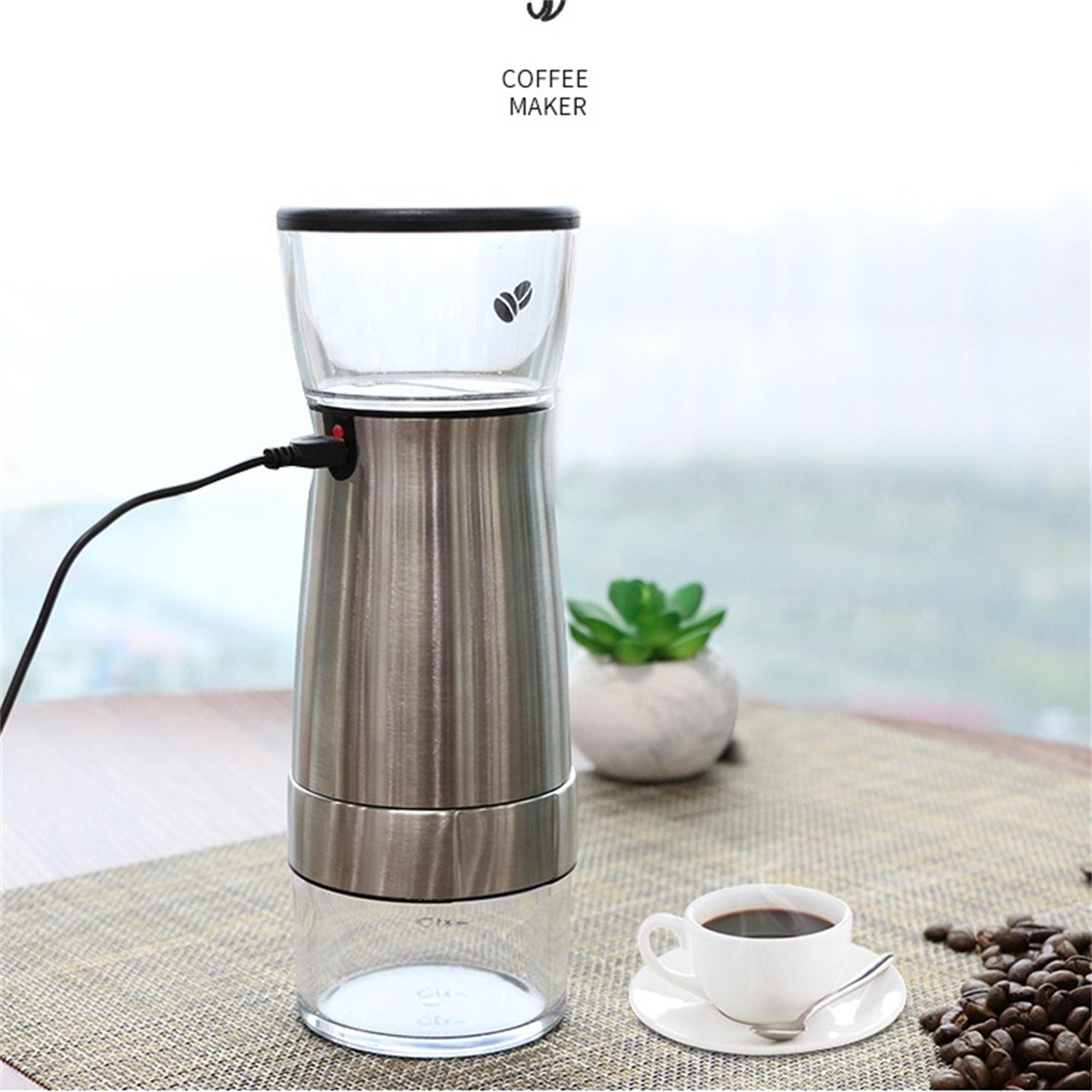 Kaffeemaschine mit Glas und Edelstahl. Eine Tasse Kaffee und Bohnen sind sichtbar.