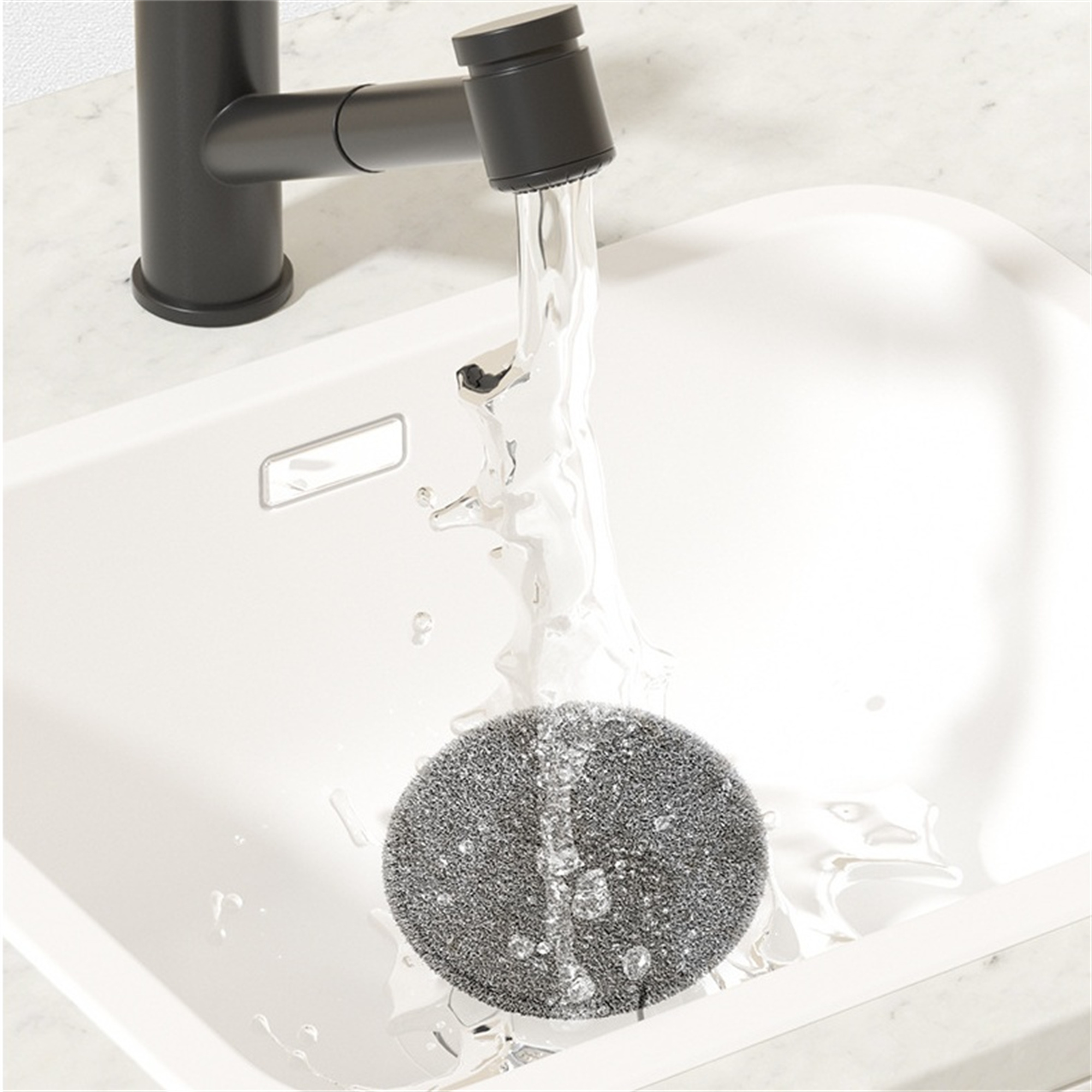Wasser fließt aus einem schwarzen Wasserhahn in ein weißes Waschbecken, mit einem grauen Schwamm.