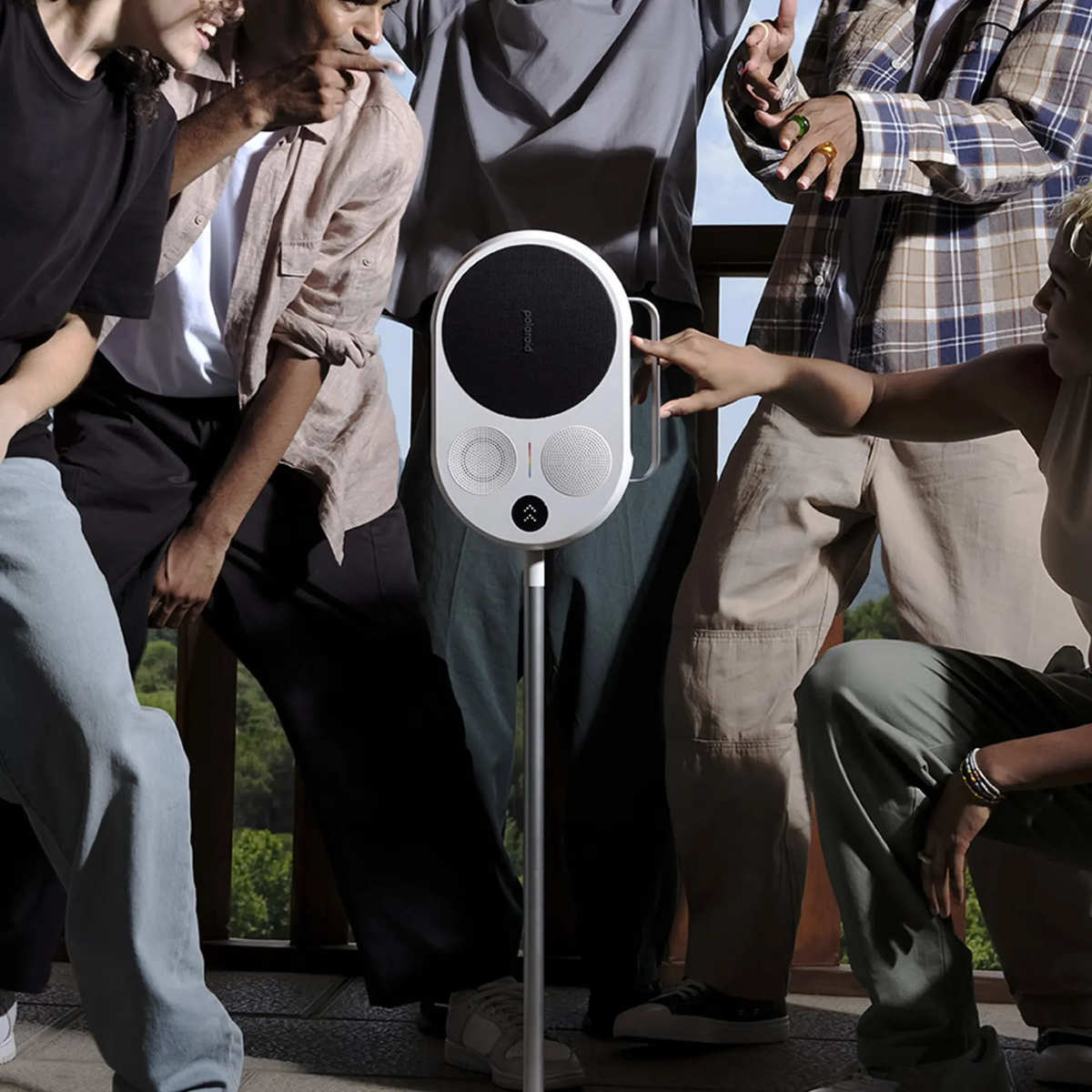 Grupa osób wokół białego głośnika na stojaku, głośnik ma czarne centrum.
