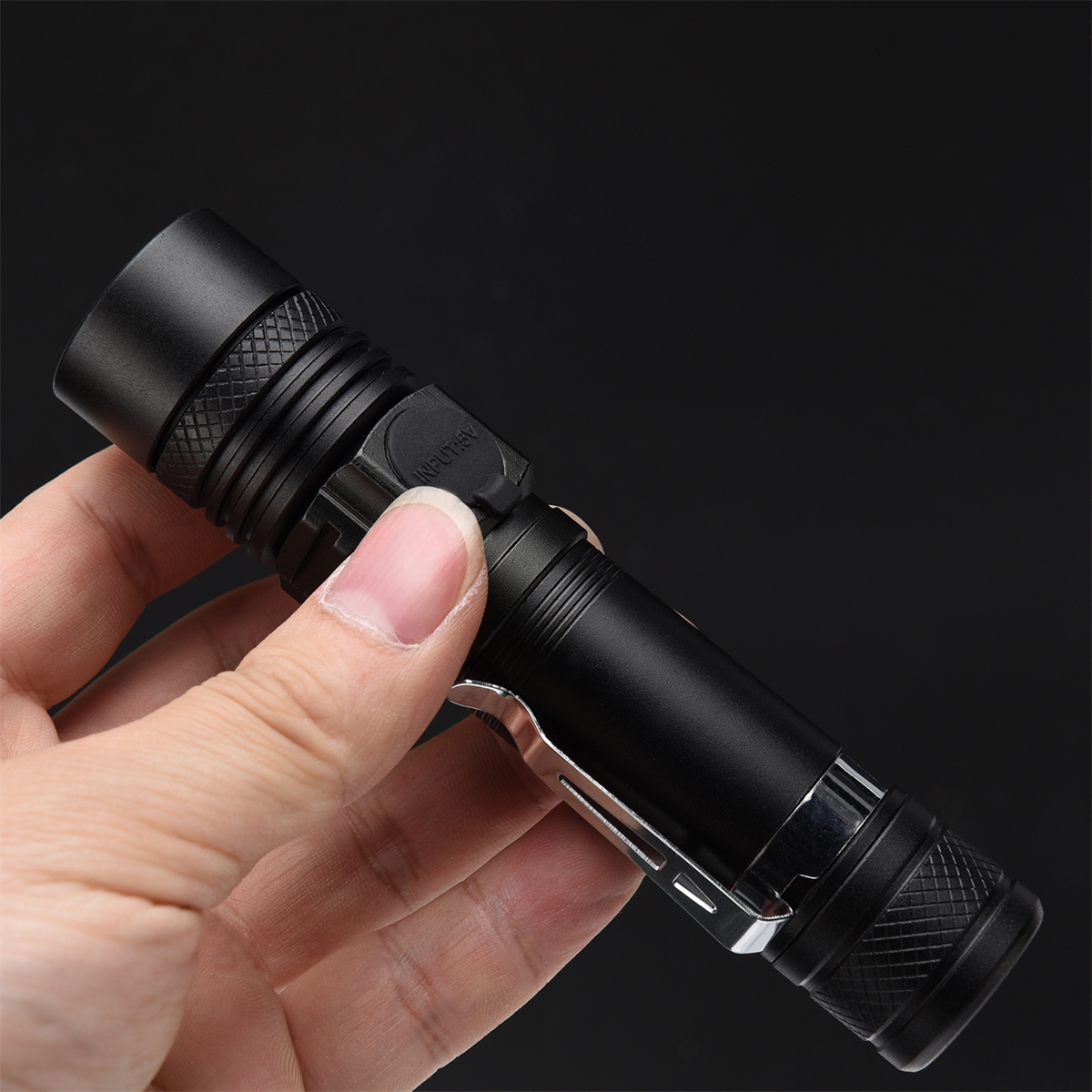 Eine schwarze Taschenlampe in der Hand gehalten. Die Taschenlampe ist zylindrisch und hat einen silbernen Clip.
