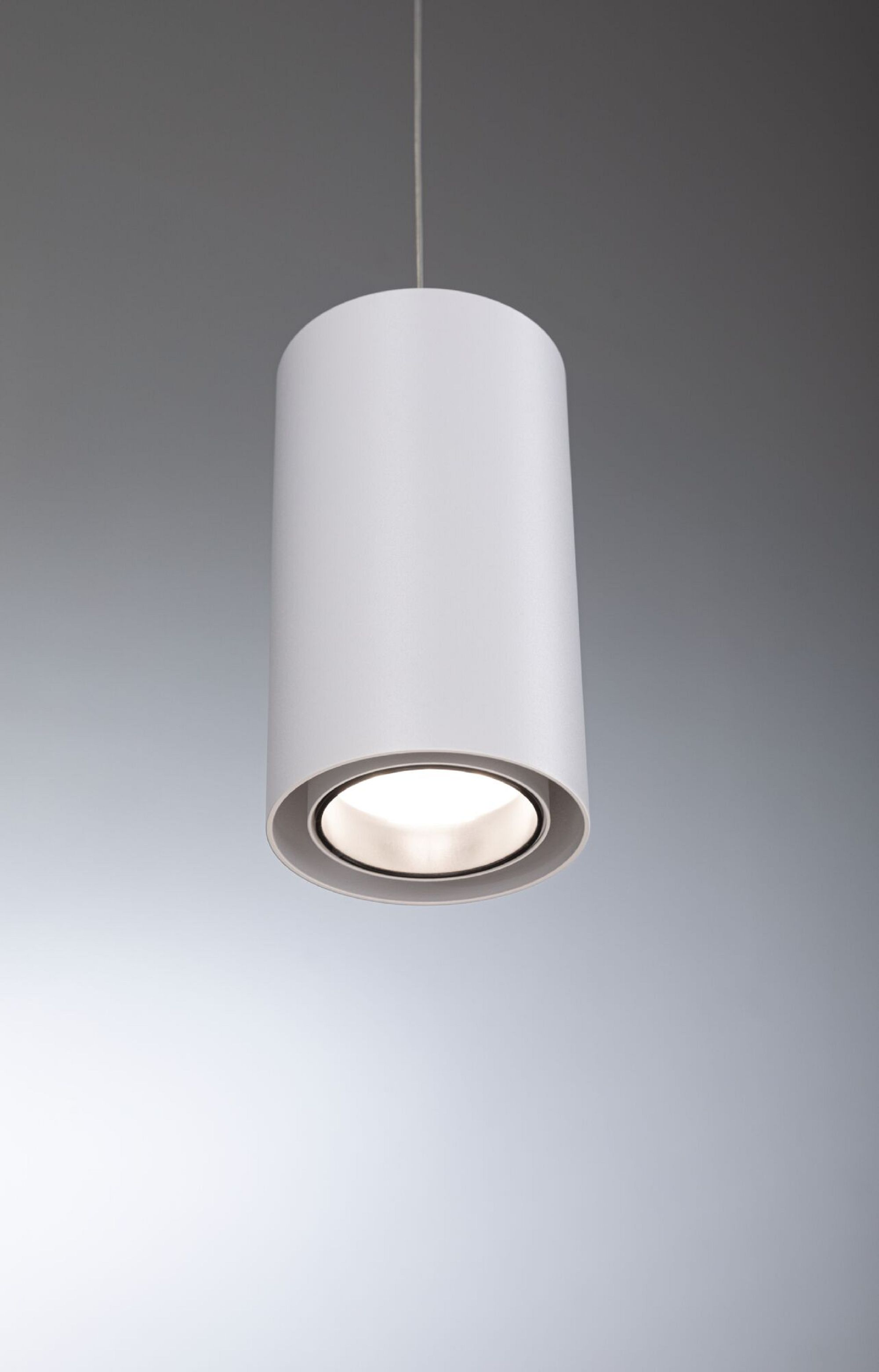 Eine weiße zylindrische Leuchte, die von der Decke hängt, mit hellem Licht.