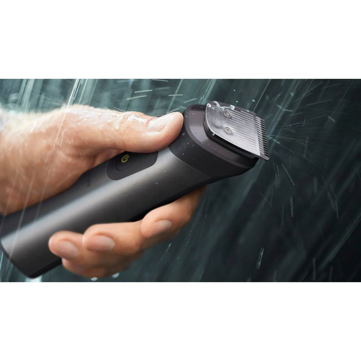 Una mano sosteniendo un recortador Philips negro y gris con gotas de agua.