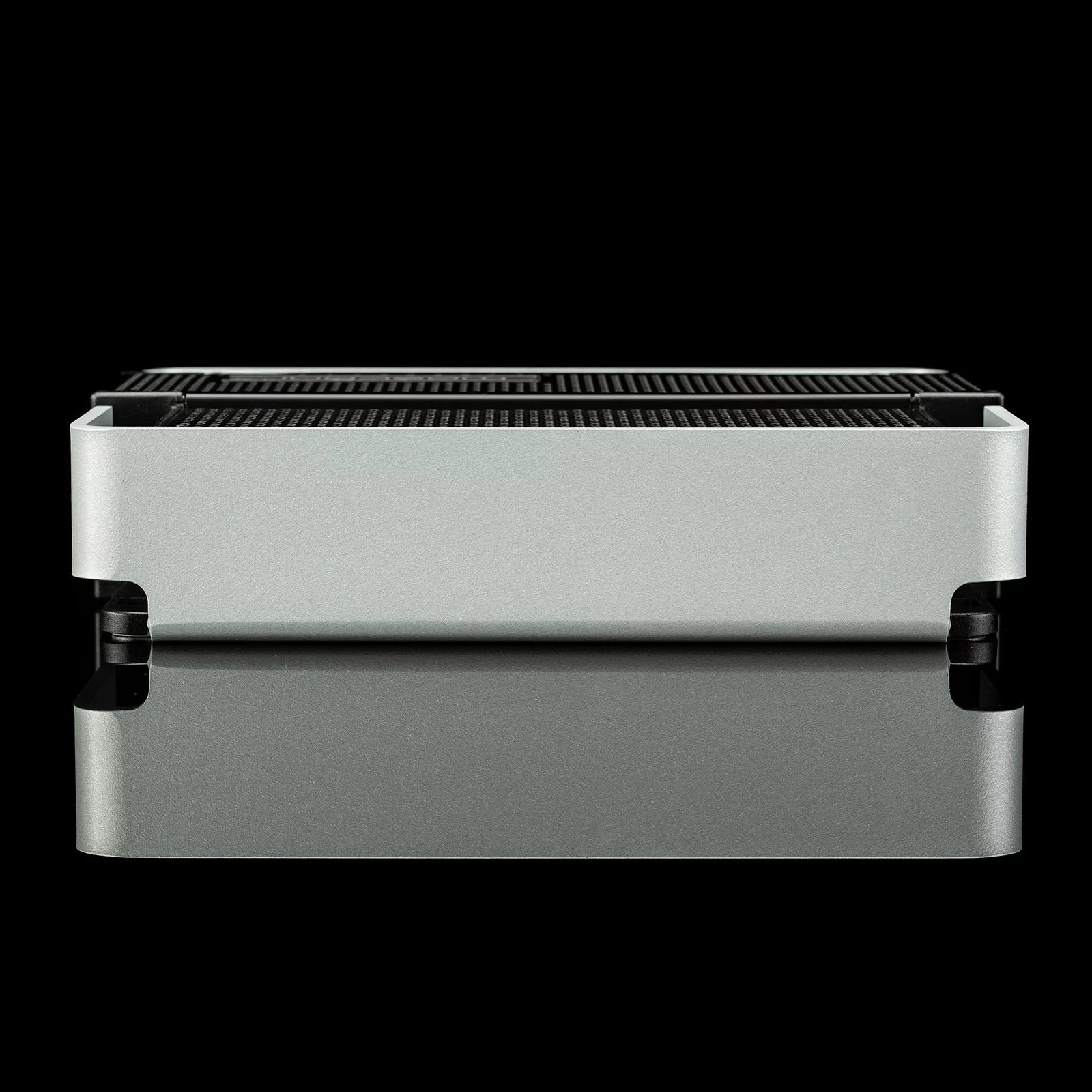 Ein silberner Grill wird auf schwarzem Hintergrund gezeigt. Der Grill spiegelt sich in der schwarzen Oberfläche.
