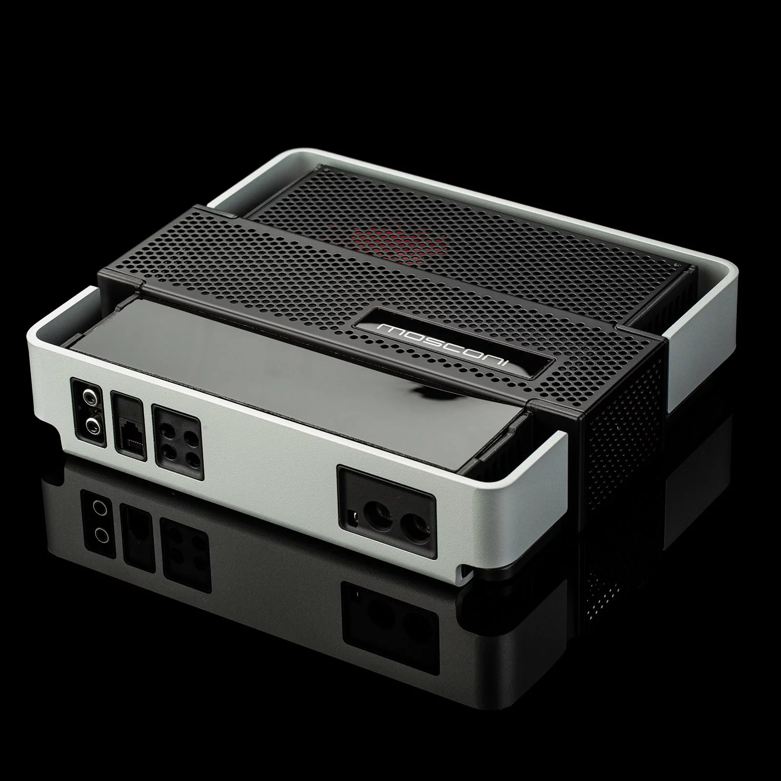 Ein silbernes und schwarzes elektronisches Gerät mit mehreren Anschlüssen. Es steht auf einer schwarzen, reflektierenden Oberfläche.