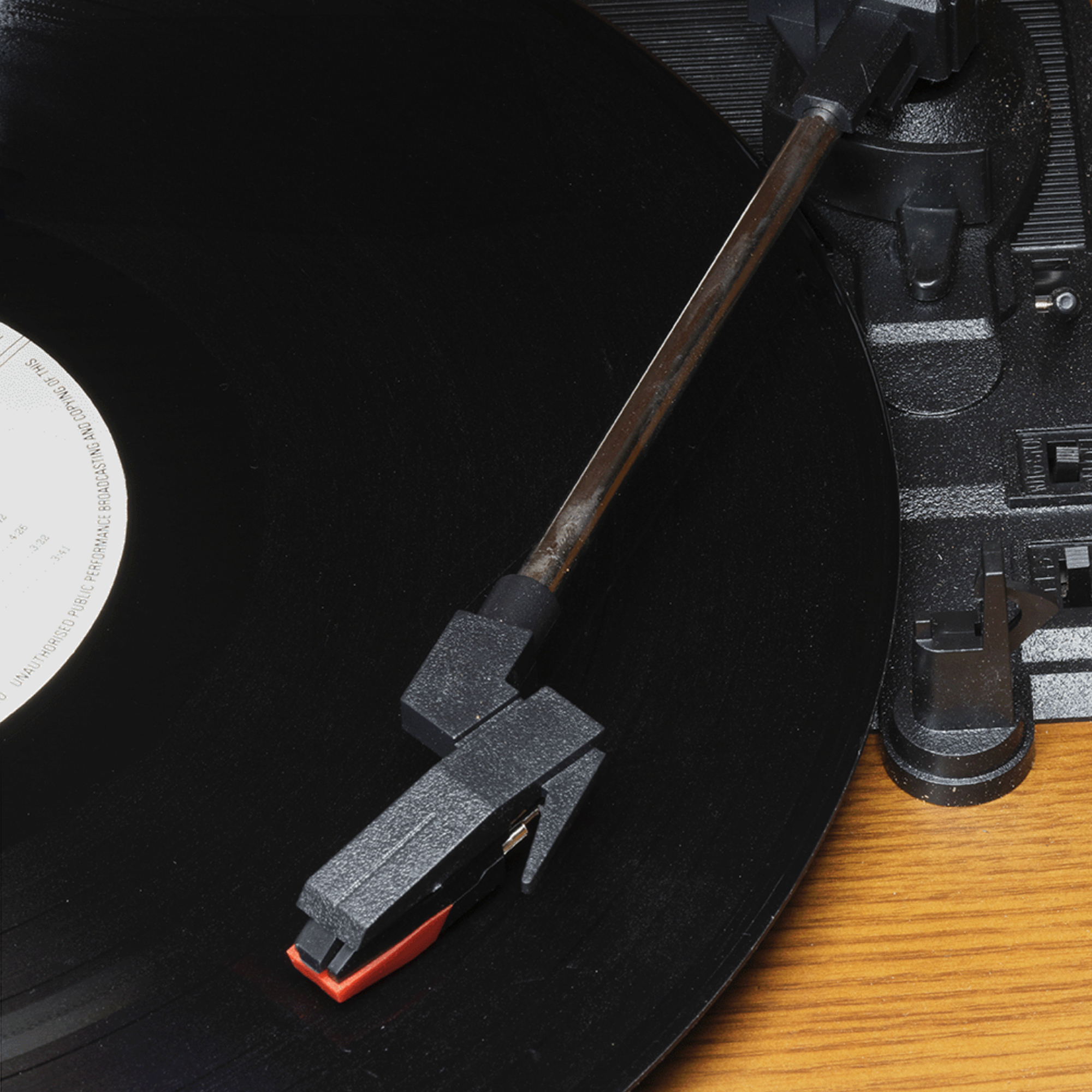 Een close-up van de naald van een platenspeler op een zwarte vinylplaat.