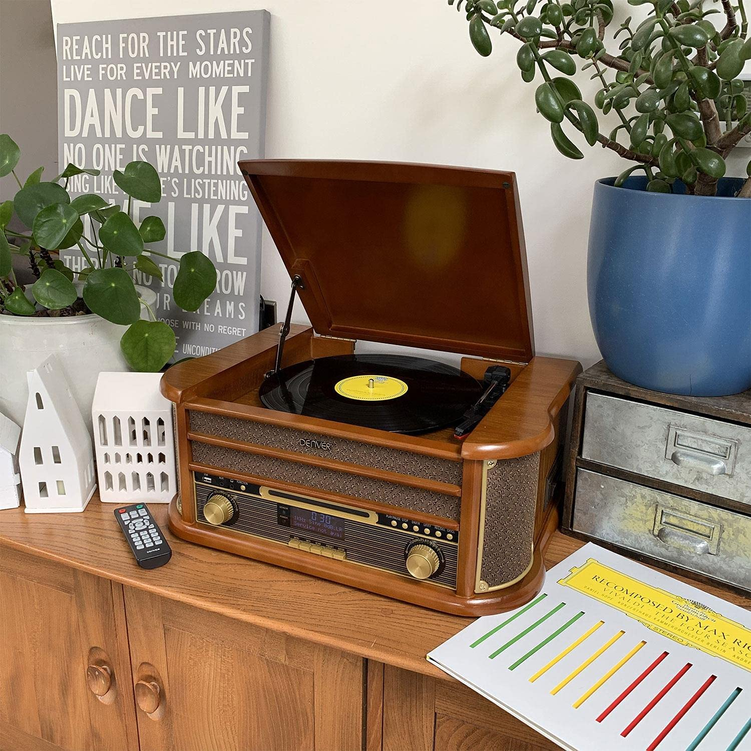 Vintage platenspeler op houten oppervlak, met planten en decor in de achtergrond.