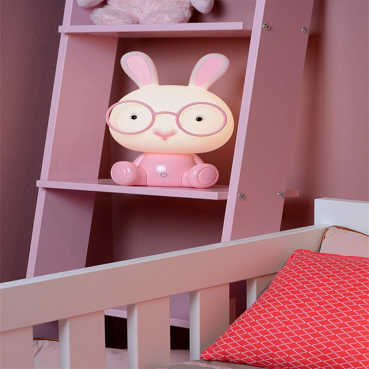 Eine rosa Hasenlampe mit Brille sitzt auf einem Regal. Eine rosa Leiter und ein Kinderbett sind im Hintergrund.