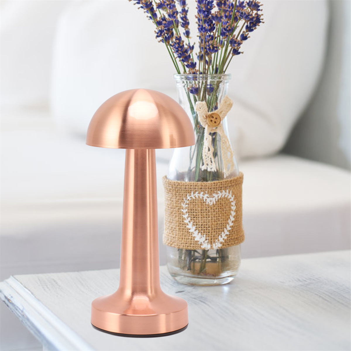 Eine Kupferlampe mit rundem Sockel steht neben einer Vase mit Lavendelblüten.