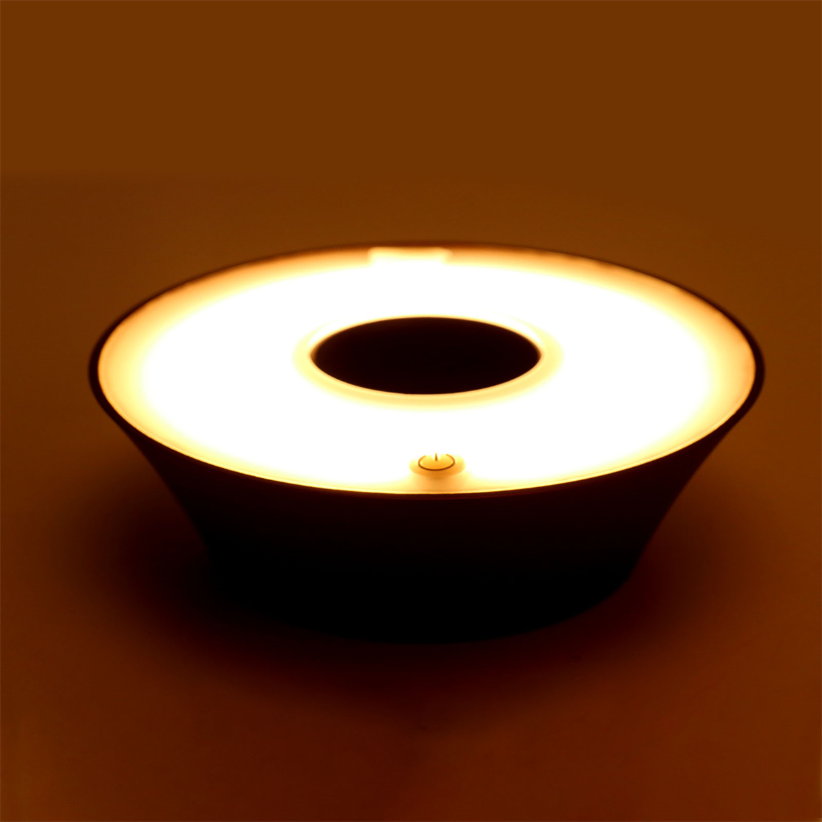 Eine dunkle, runde Lampe mit hellem weißem Lichtring und kleinem Einschaltknopf.
