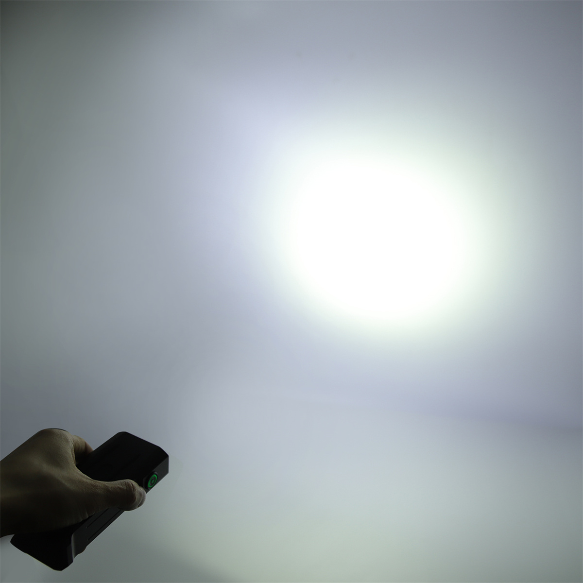 Eine Hand, die eine Taschenlampe hält und einen hellen Lichtstrahl vor hellem Hintergrund aussendet.