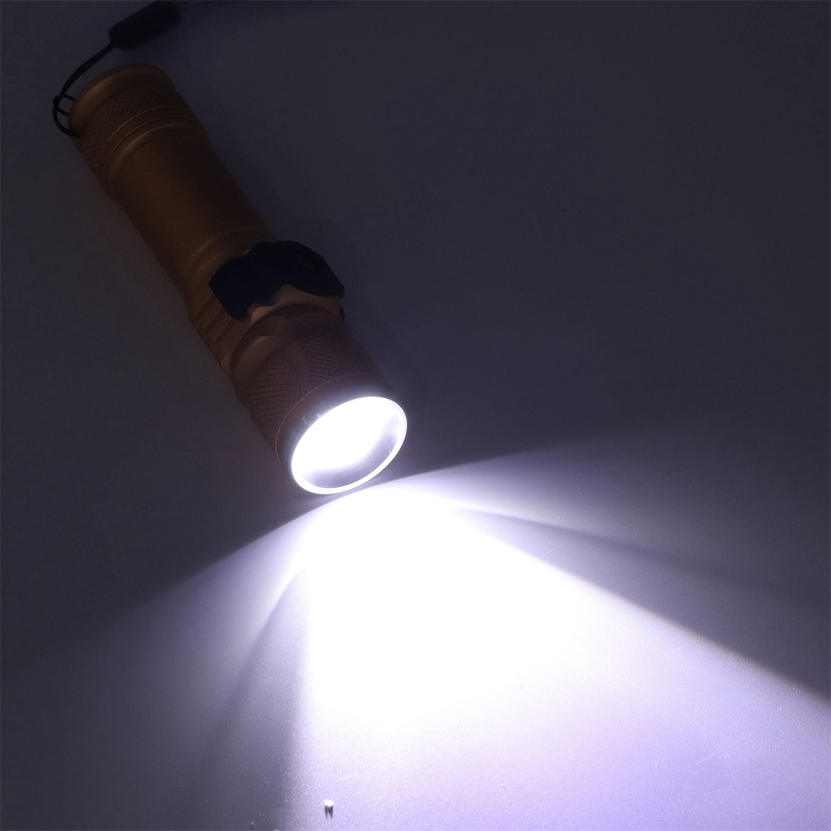 Goldene Taschenlampe, die einen hellen, weißen Lichtstrahl aussendet, abgewinkelt auf dunkler Oberfläche.