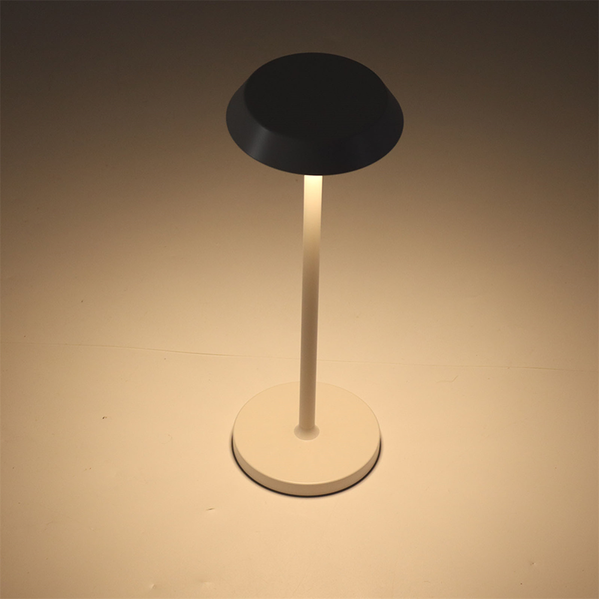 Weiße Lampe mit schwarzem Aufsatz auf weißer Oberfläche.