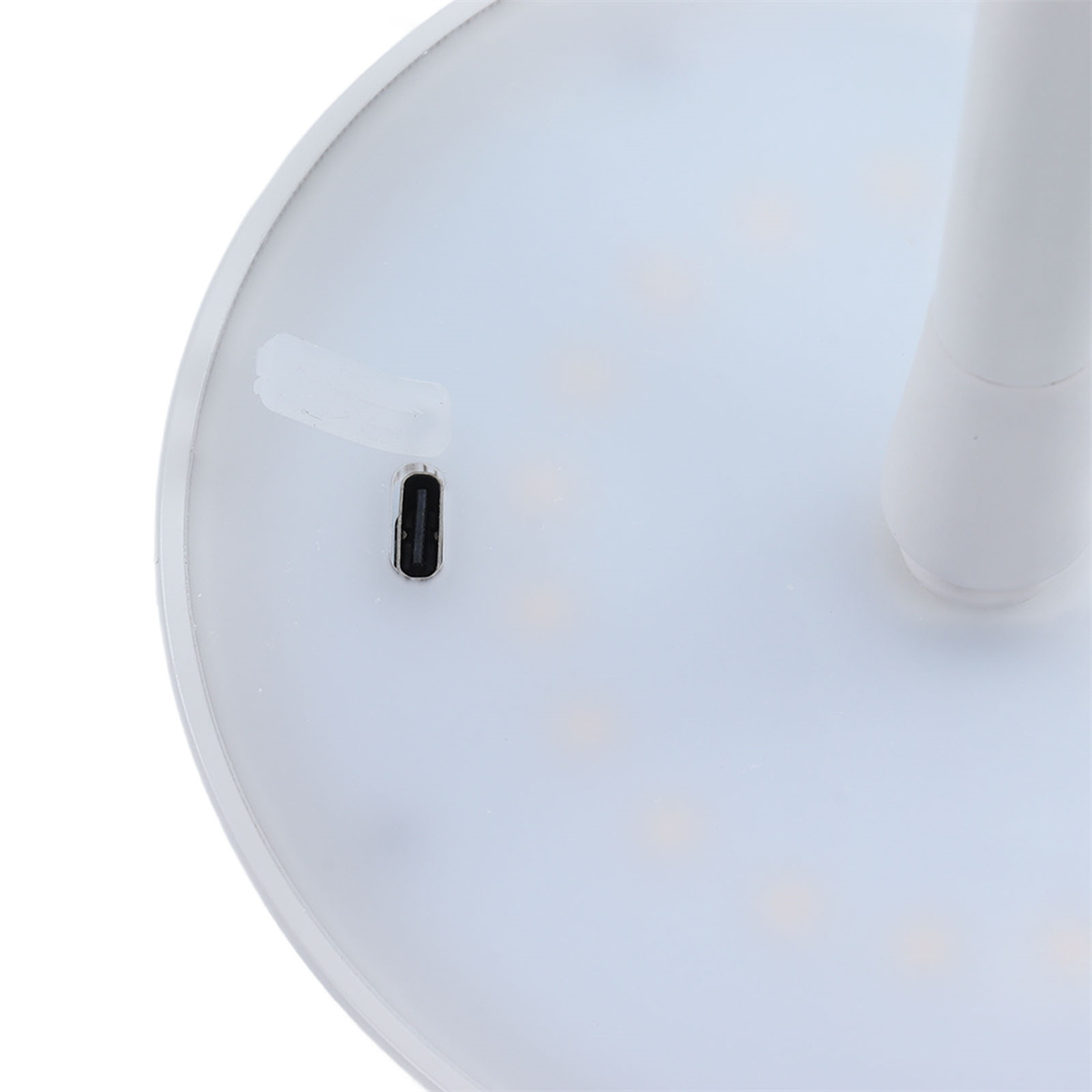 Nahaufnahme des Sockels einer weißen Lampe mit USB-Anschluss auf weißem Grund.