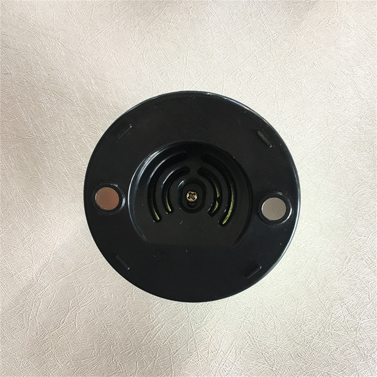 Schwarzer, kreisförmiger Gerätefuß mit zwei silbernen Magneten und einer zentralen Schraube.