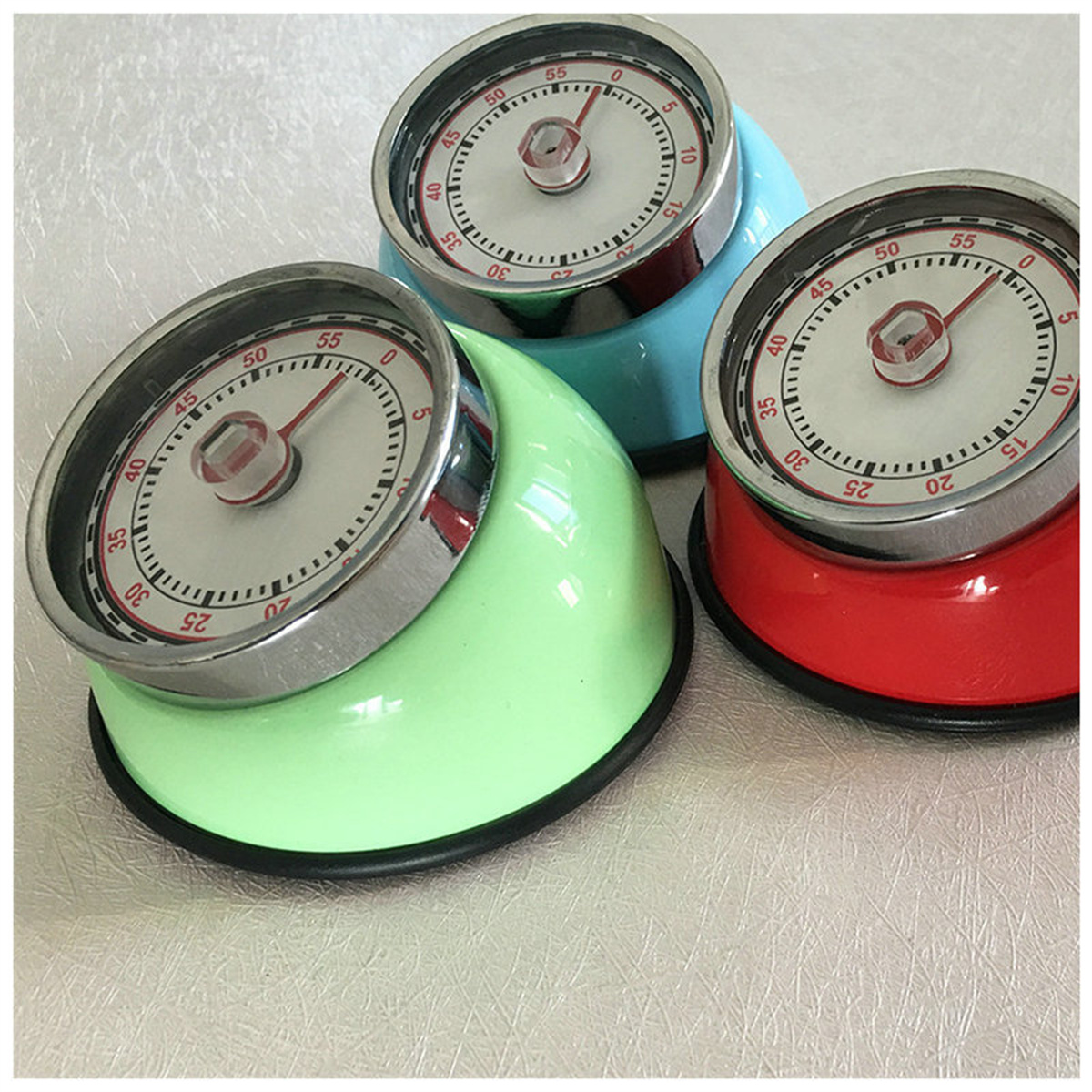 Drei bunte Retro-Küchenwecker in Grün, Blau und Rot, die Zeit anzeigen.