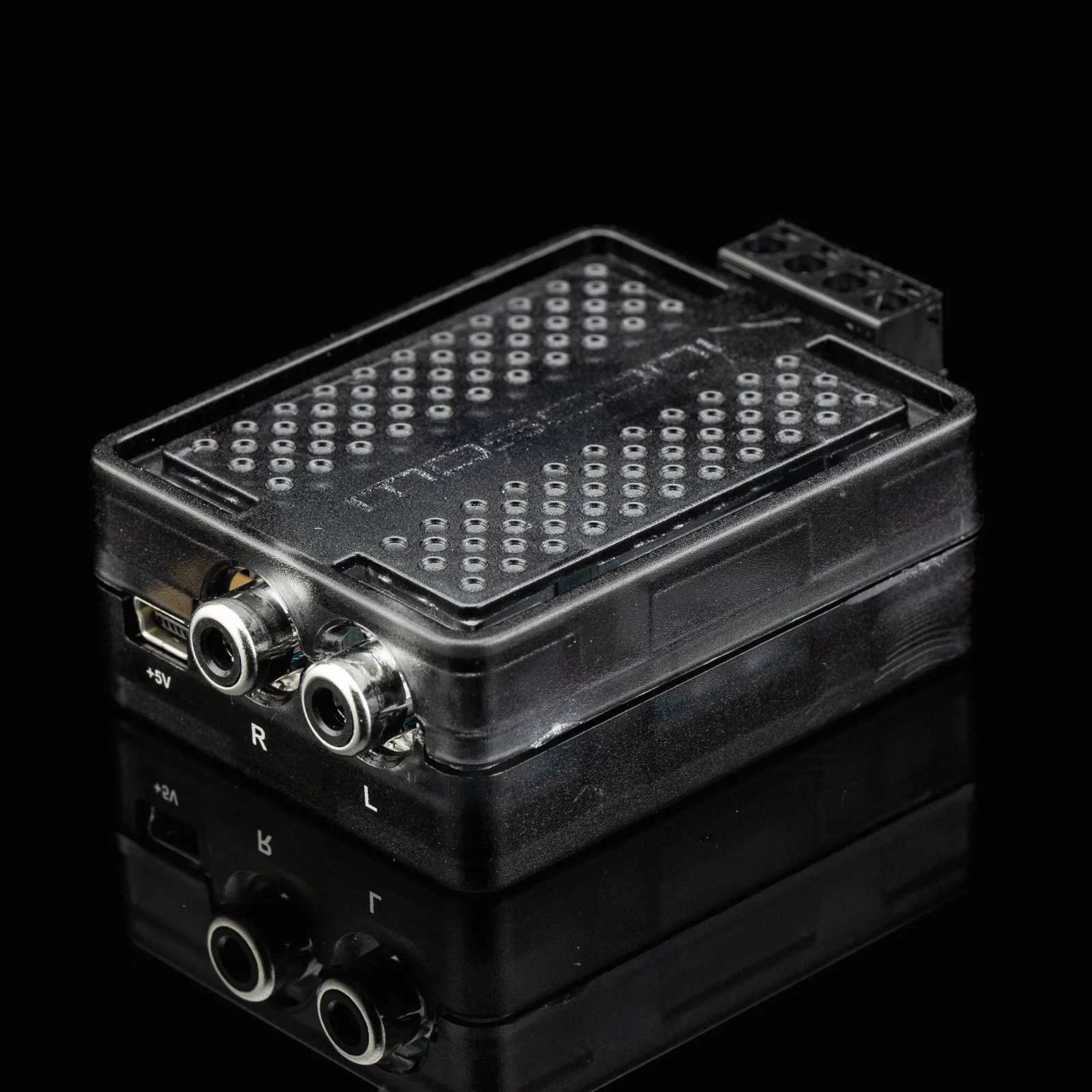 Schwarzes elektronisches Gerät mit Anschlüssen und Beschriftungen für Audioeingang und Strom (+5V).