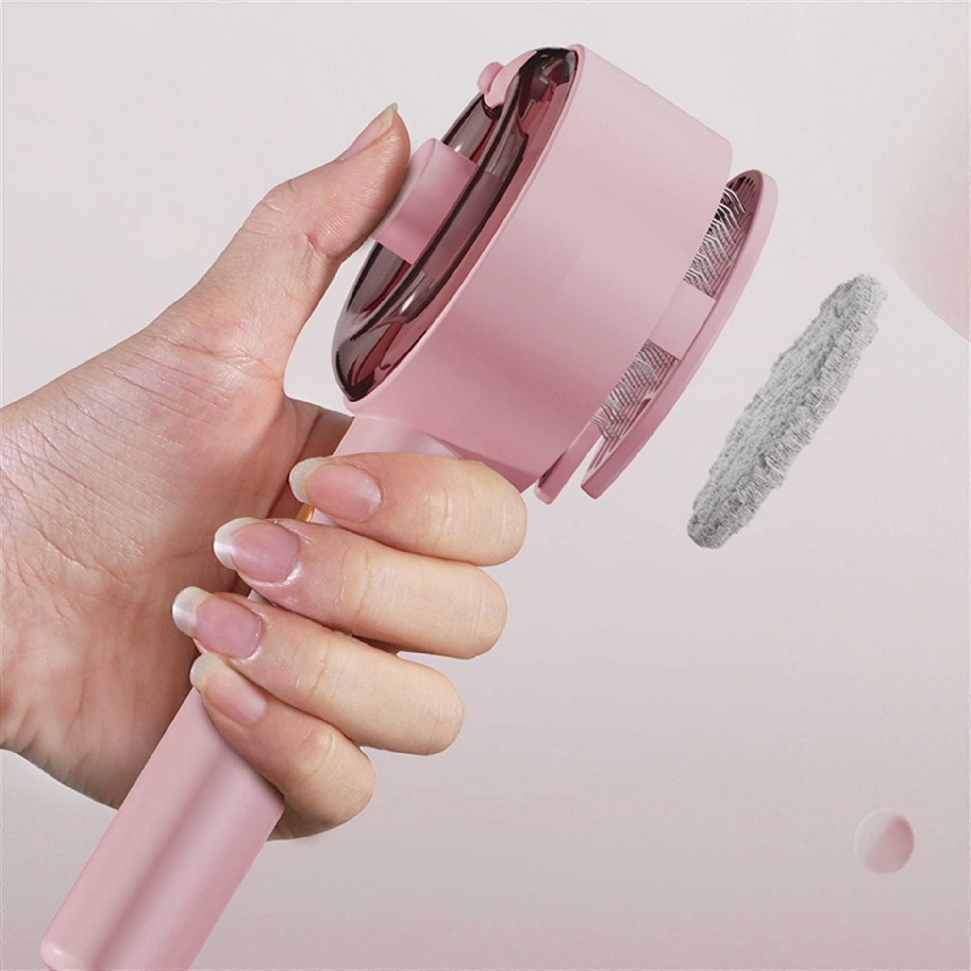 Ein rosa Handgerät mit rosa Griff und abnehmbarem Reinigungs-Pad.