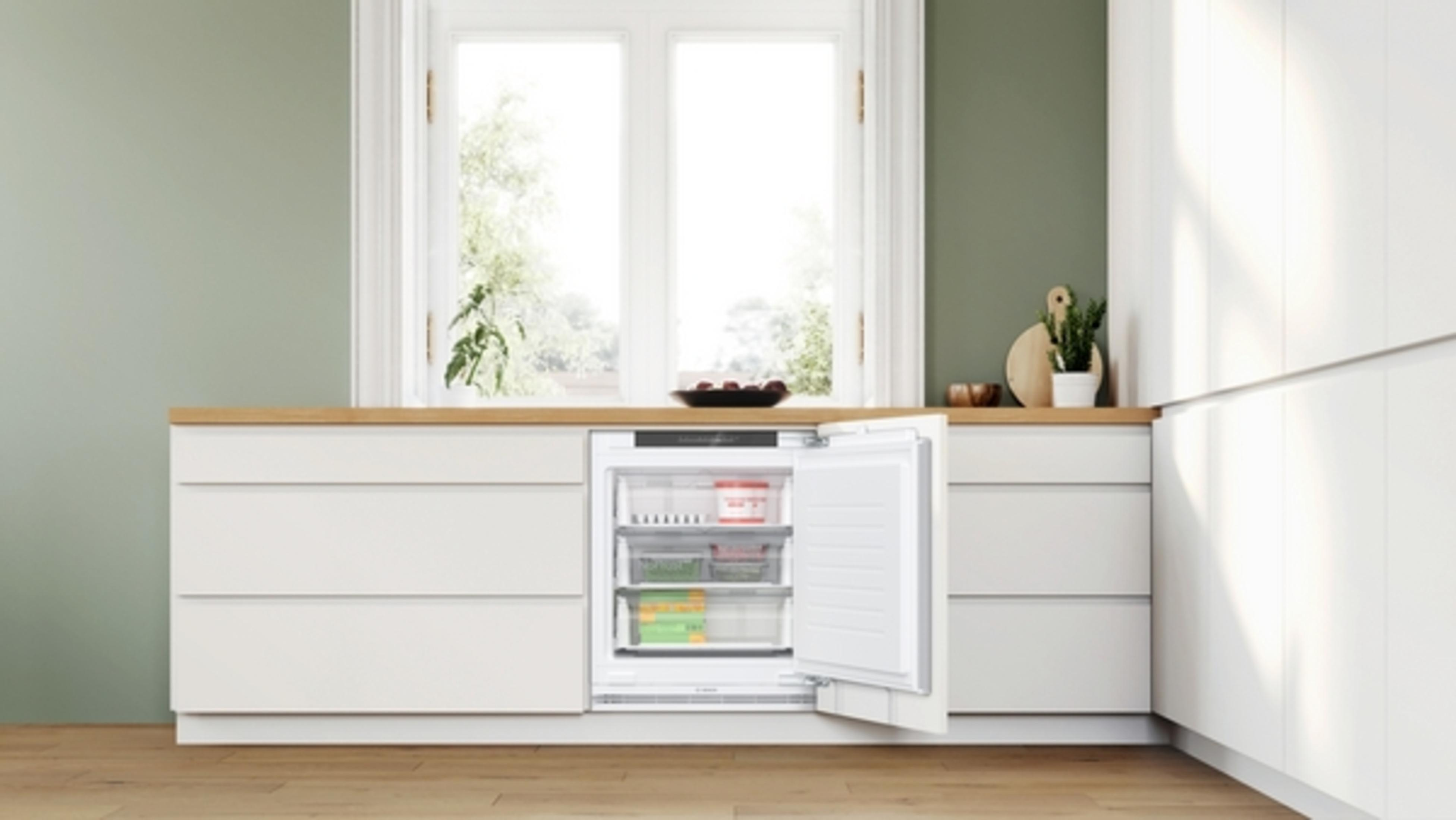 White kitchen scene with an open refrigerator. Wooden countertop and wooden floor are visible.
